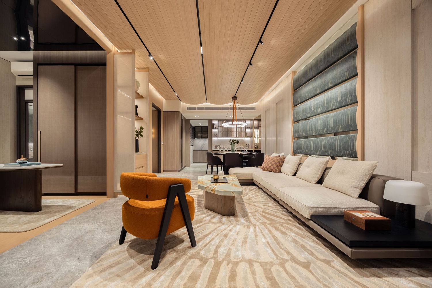 Luxurious modern living room featuring an orange accent chair, beige sectional sofa, wood-paneled ceiling, and elegant neutral decor.