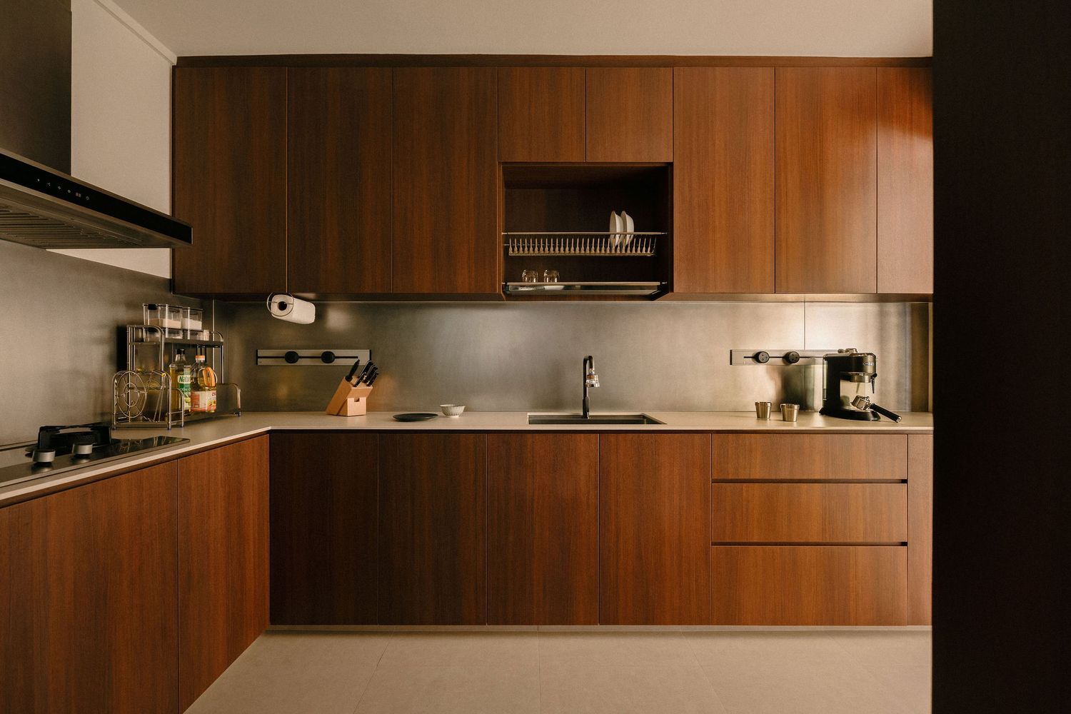 Modern L-shaped kitchen with warm walnut wood cabinets, stainless steel backsplash, undermount sink, open shelf and built-in extractor hood.