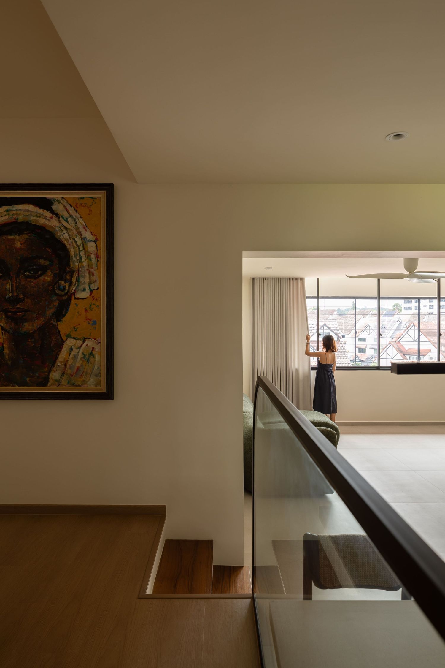 Interior view of a modern minimalist hallway with white walls, wooden flooring, and dark handrails leading to a bright window.