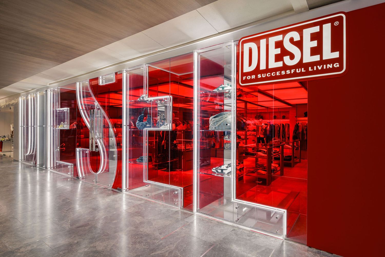 Diesel fashion store entrance featuring bold red illuminated signage and glass facade displaying the brand logo.