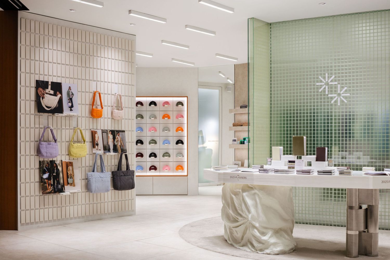 Modern retail store interior with mint green tile wall, white textured panels, and hanging merchandise displays.