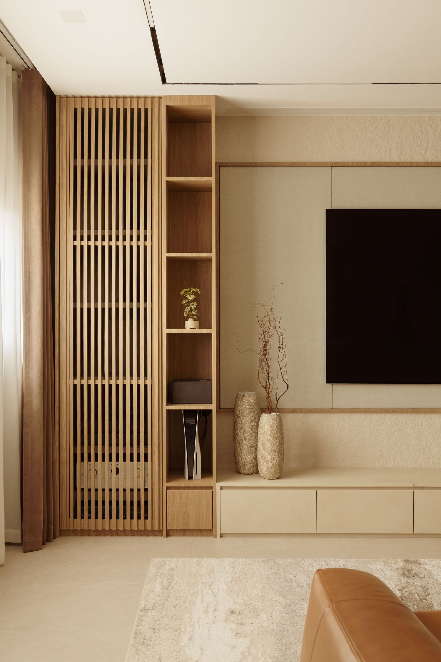 Modern minimalist living room with wooden slatted panel, built-in shelving, and wall-mounted TV in neutral beige tones.