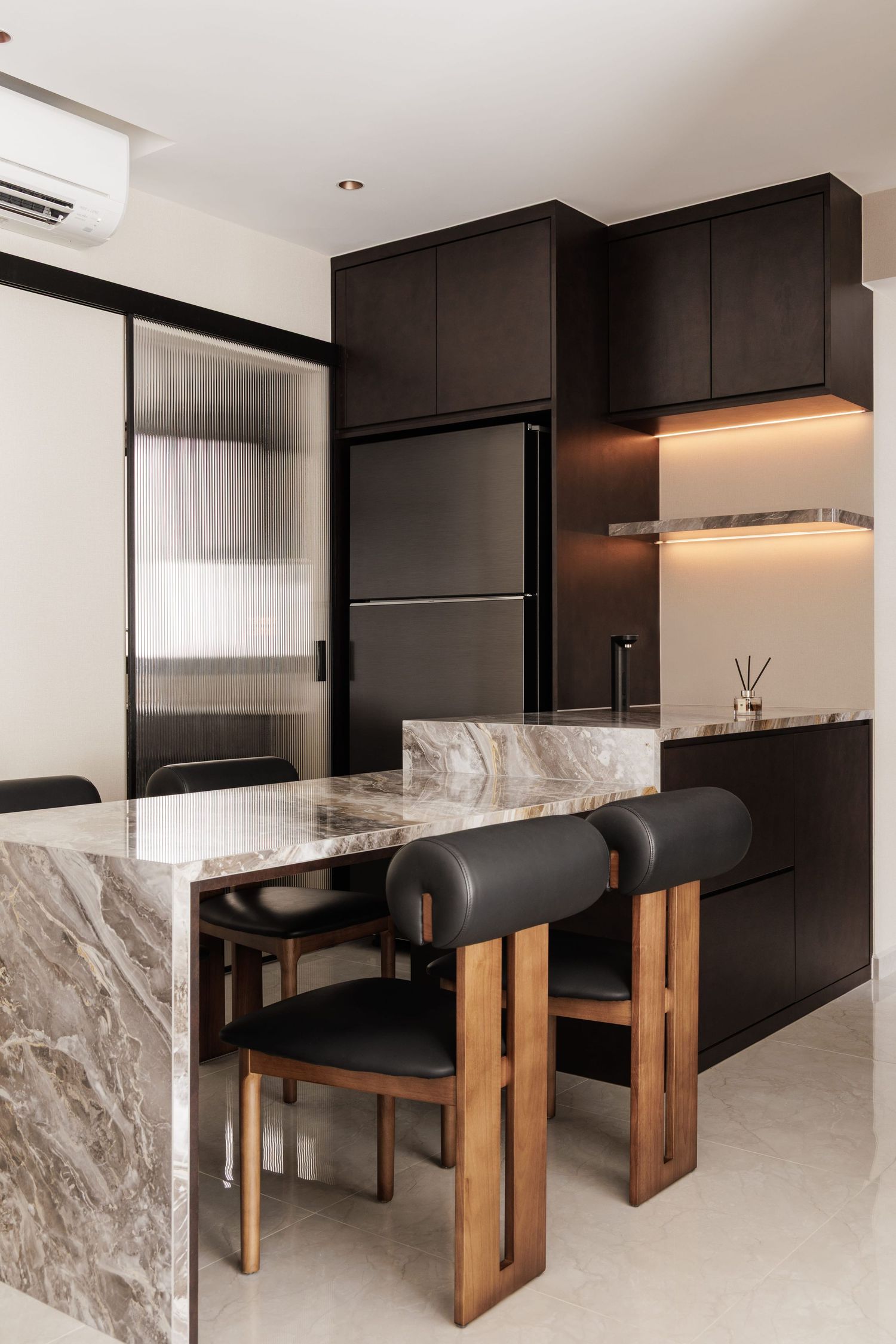 Modern kitchen design with black cabinets, marble island, and wooden dining chairs featuring sleek minimalist aesthetics.