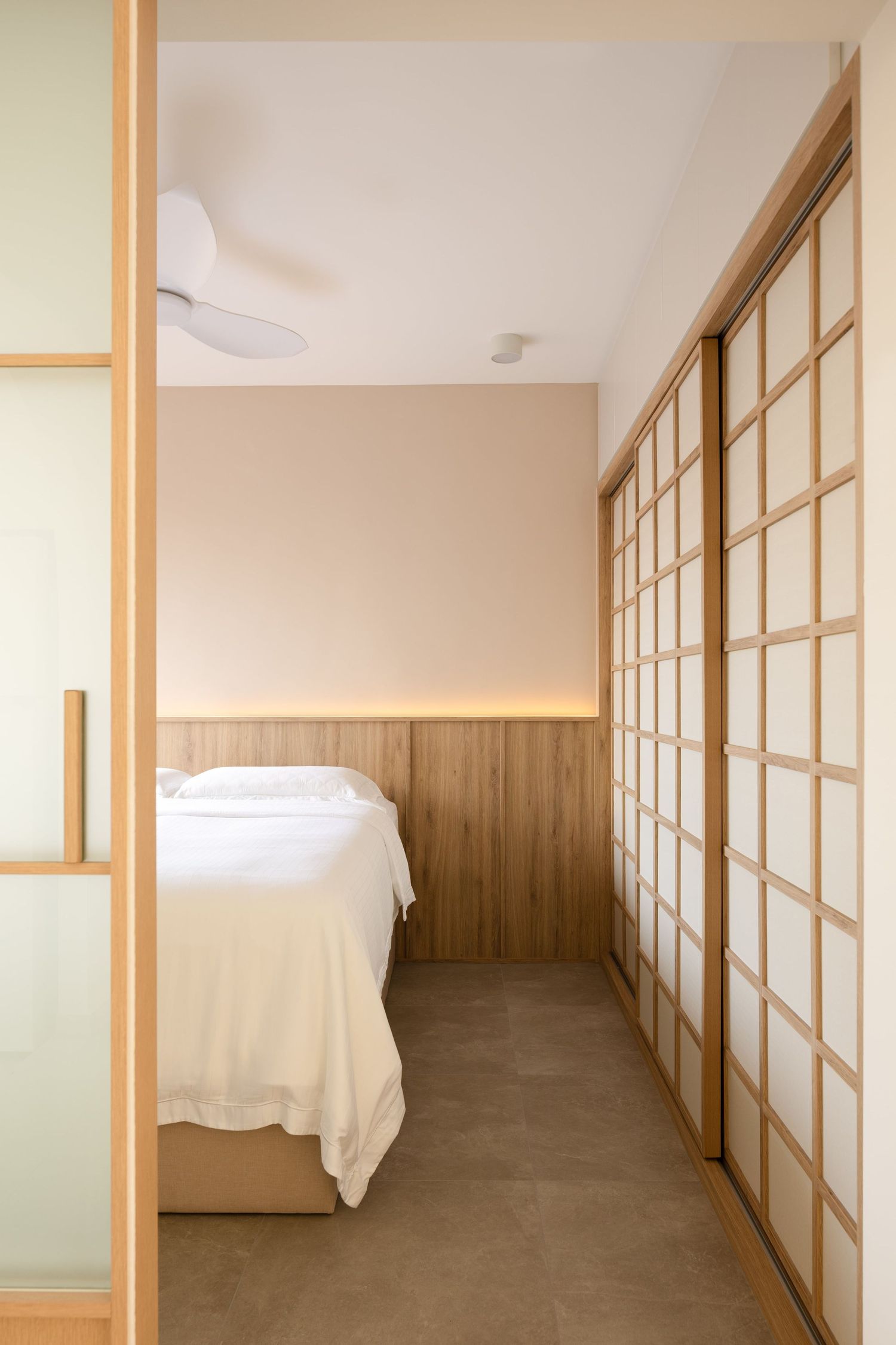 Minimalist Japanese-style hallway with sliding shoji screens and wooden accents leads to a bright bedroom space.