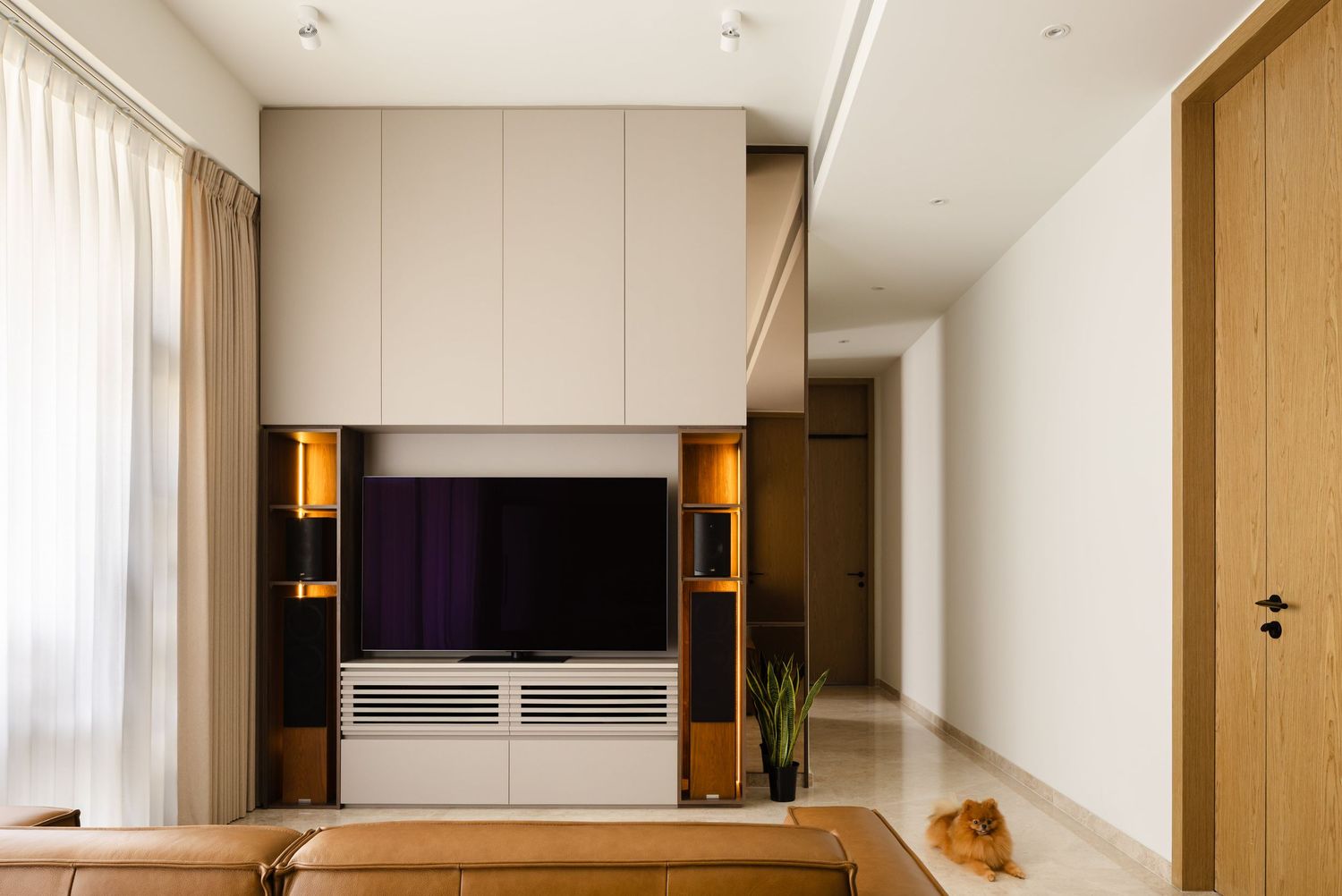 Modern living room interior with wall-mounted TV, wooden accents, and sheer curtains in a minimalist contemporary design.