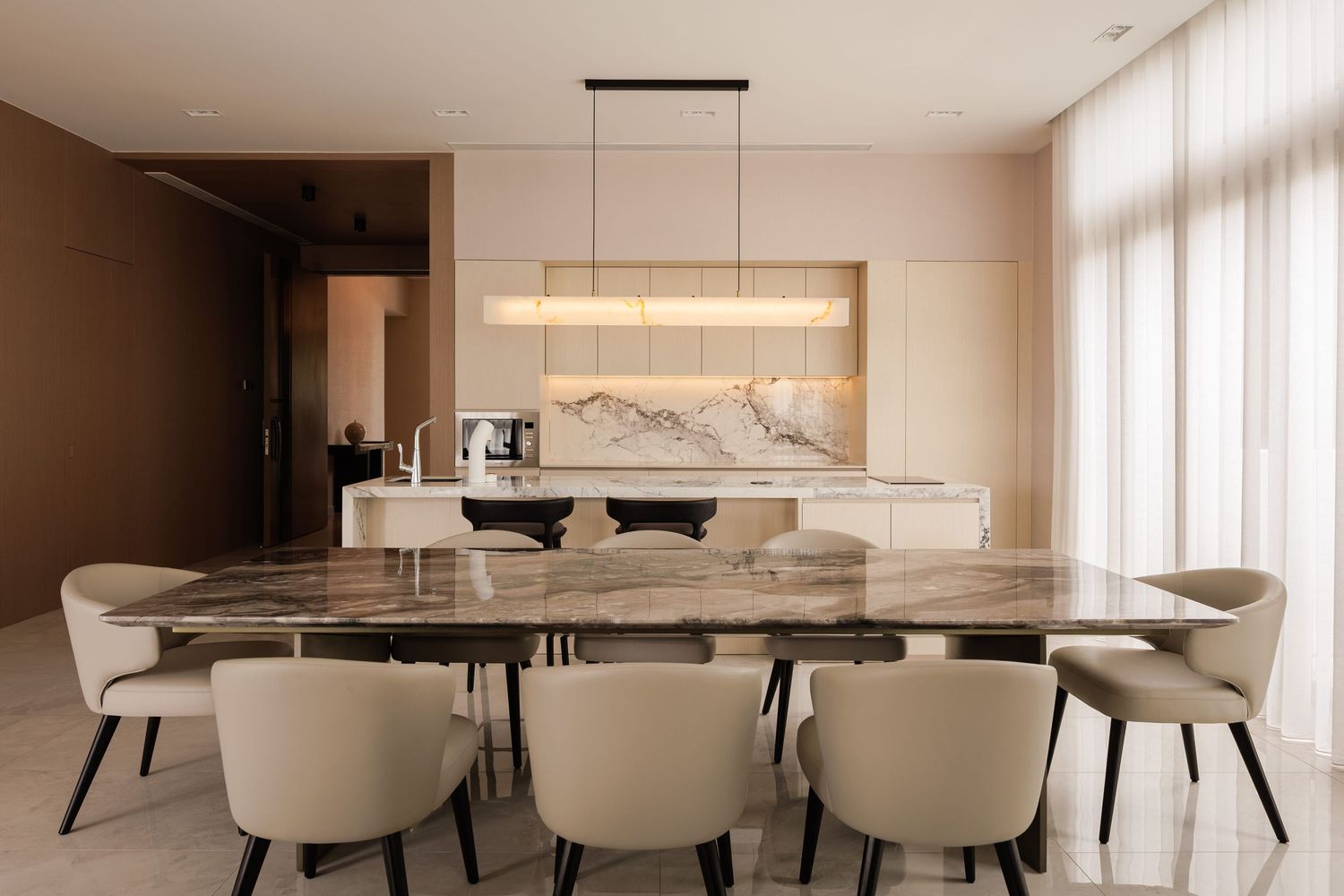 A contemporary dining room features a sleek white marble table with cream leather chairs and warm accent lighting.