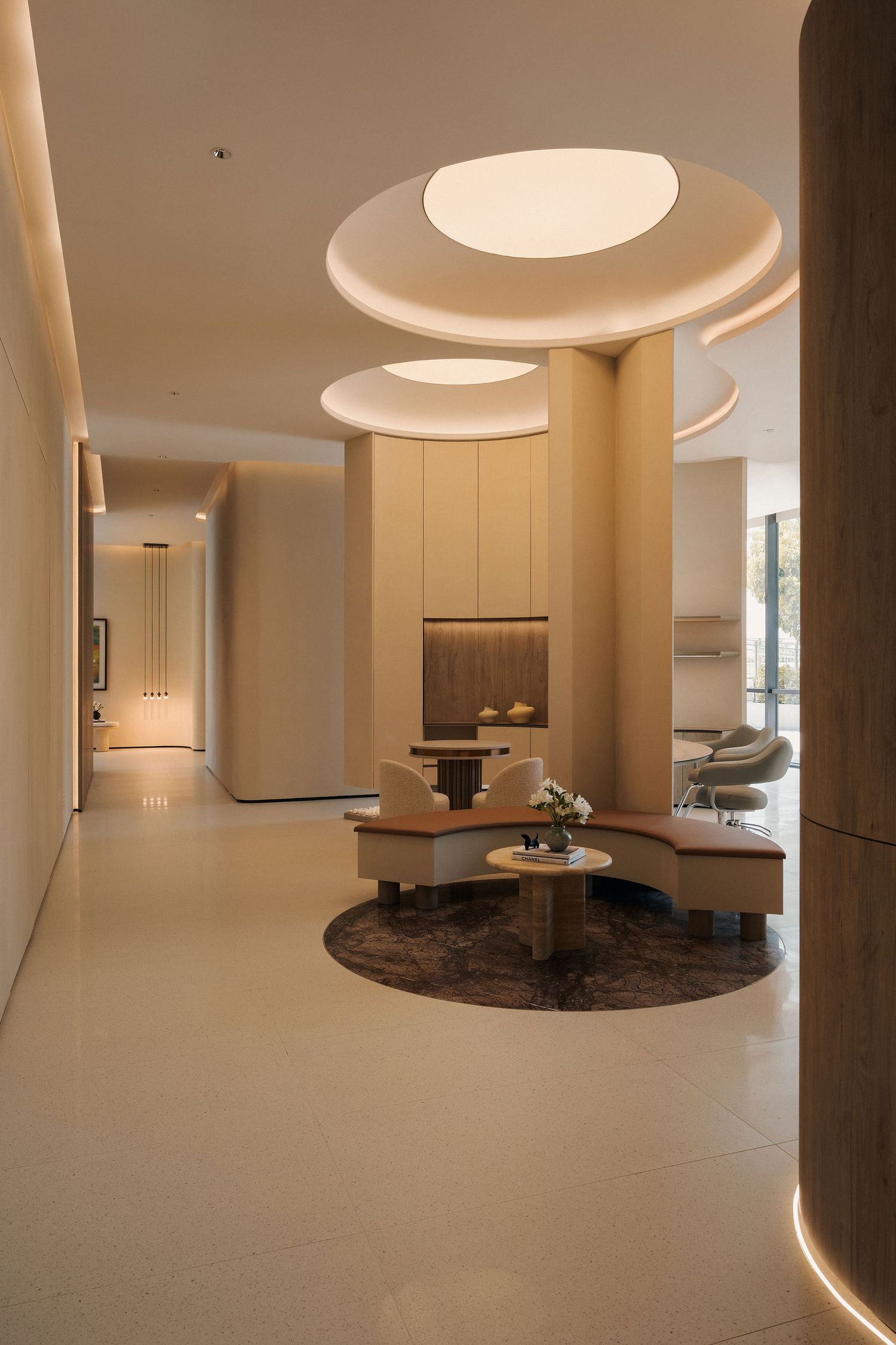 Modern luxury hotel lobby with circular ceiling lights, curved seating, and warm neutral tones creating an elegant welcoming space.