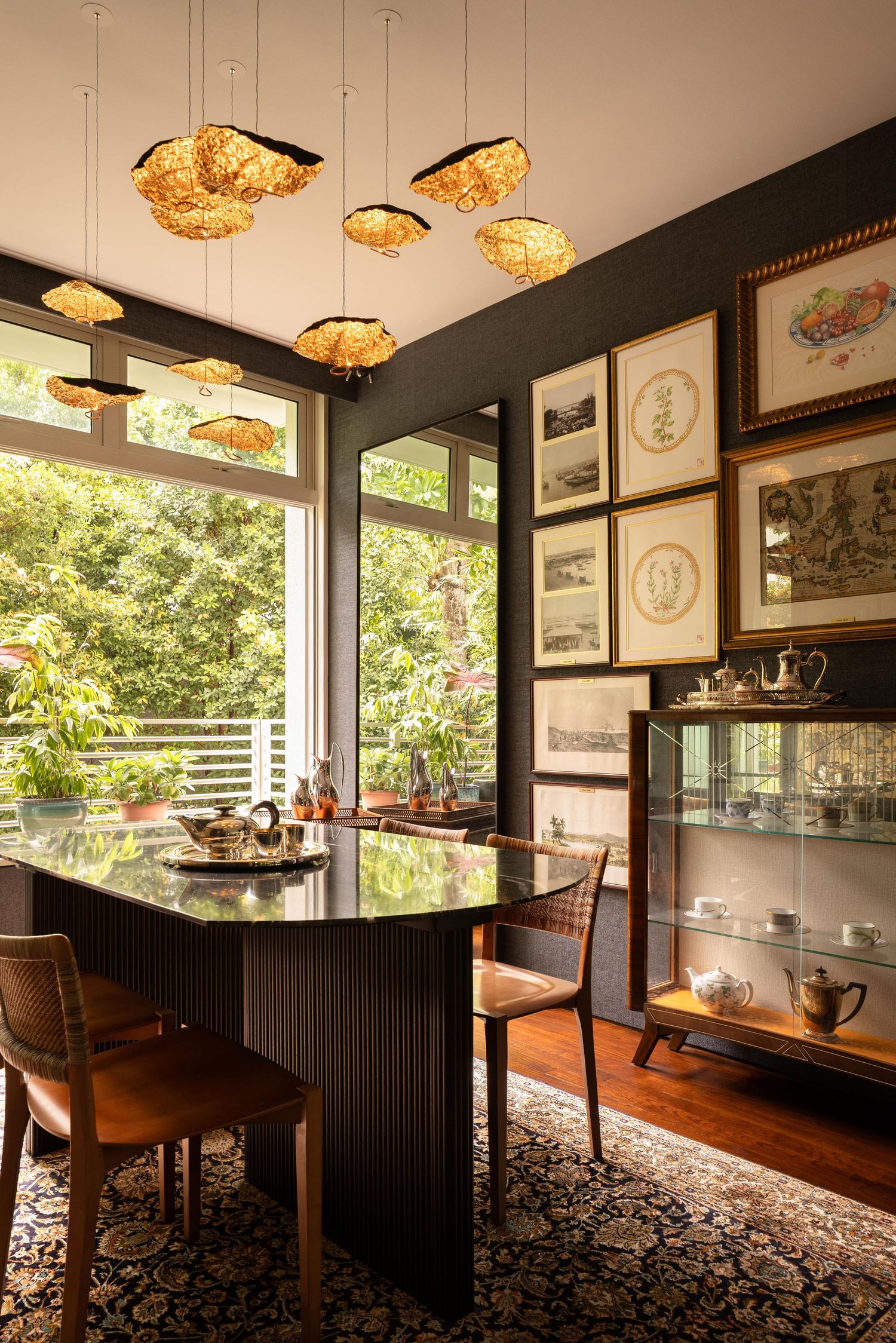 Modern home interior with black wainscoting features unique pendant lights and wooden furniture in a sun-lit dining space.
