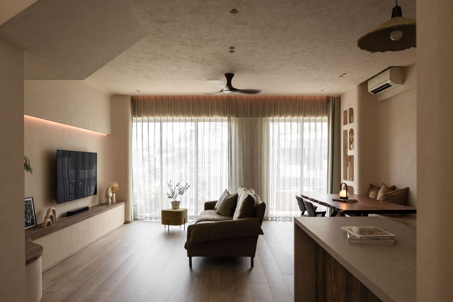 A modern minimalist living room with white walls features ceiling fans and large windows letting in natural light.