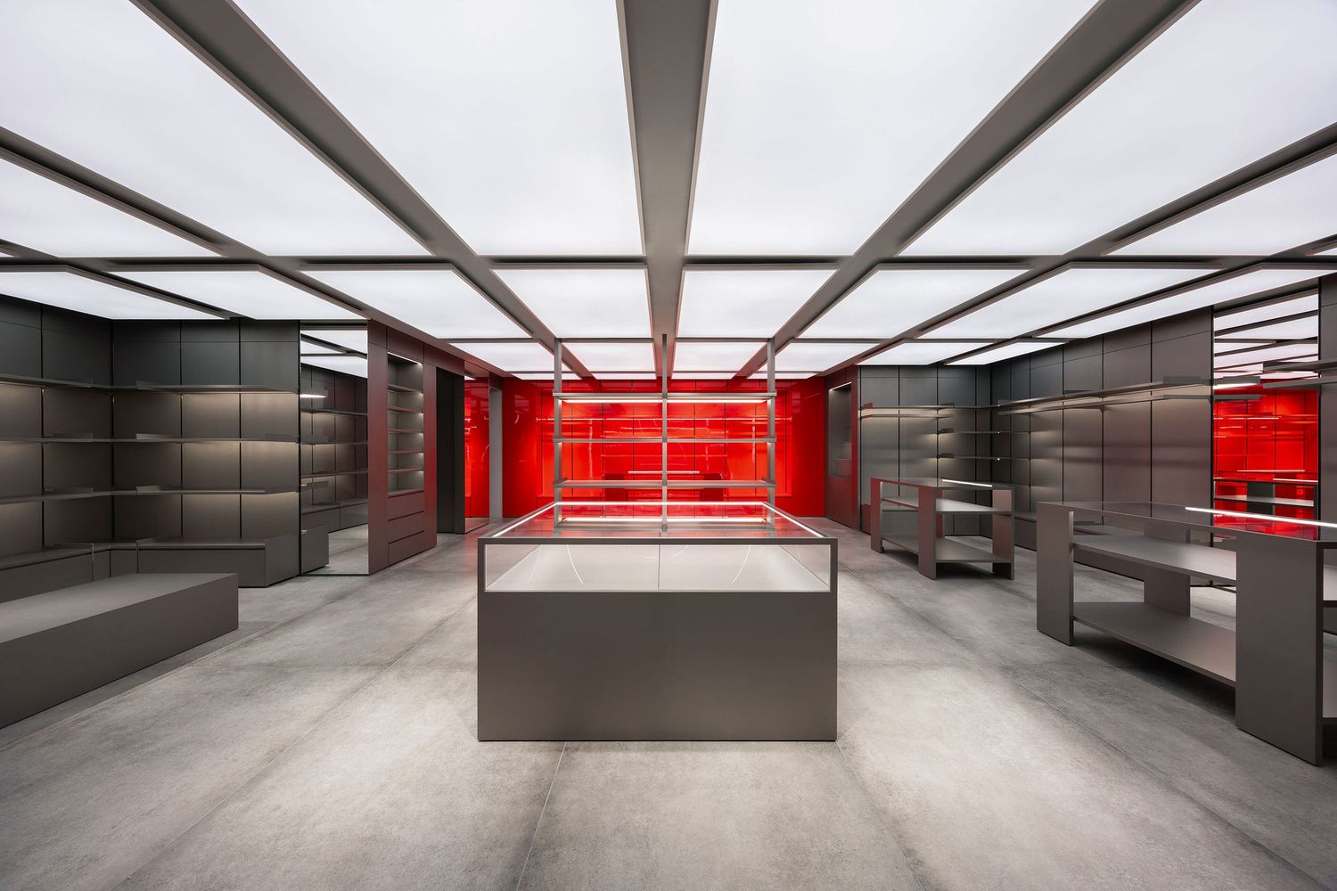 Modern retail interior with red illuminated display cases, gray shelving units, and sleek concrete floors under a bright ceiling.