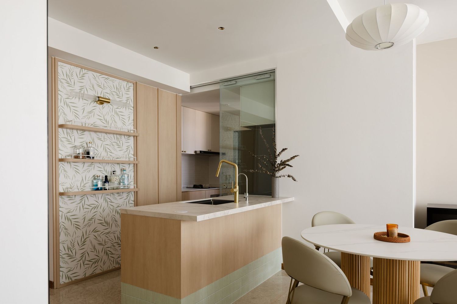 Modern minimalist kitchen with light wood cabinets, marble pattern wallpaper, white walls and round dining table setup.