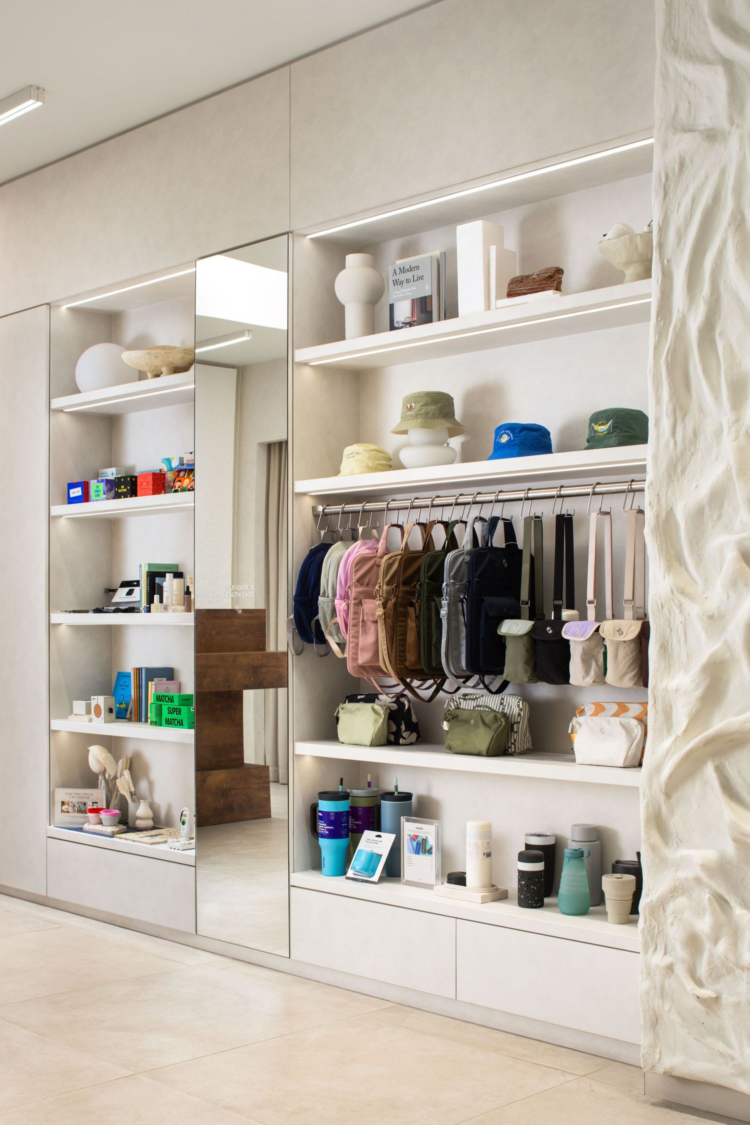 Modern white built-in closet with organized shelving displaying clothing, hats, accessories and storage items.