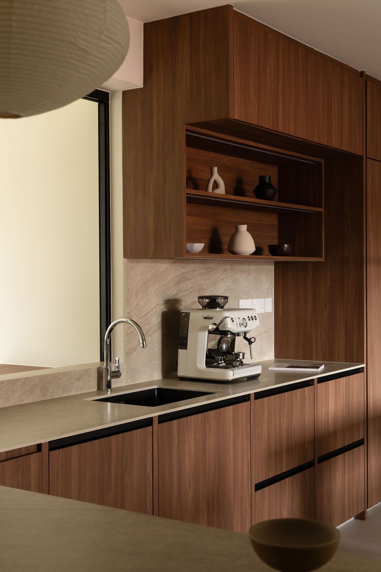 Modern kitchen interior with sleek walnut wood cabinetry and black countertops showcasing minimalist floating shelves.