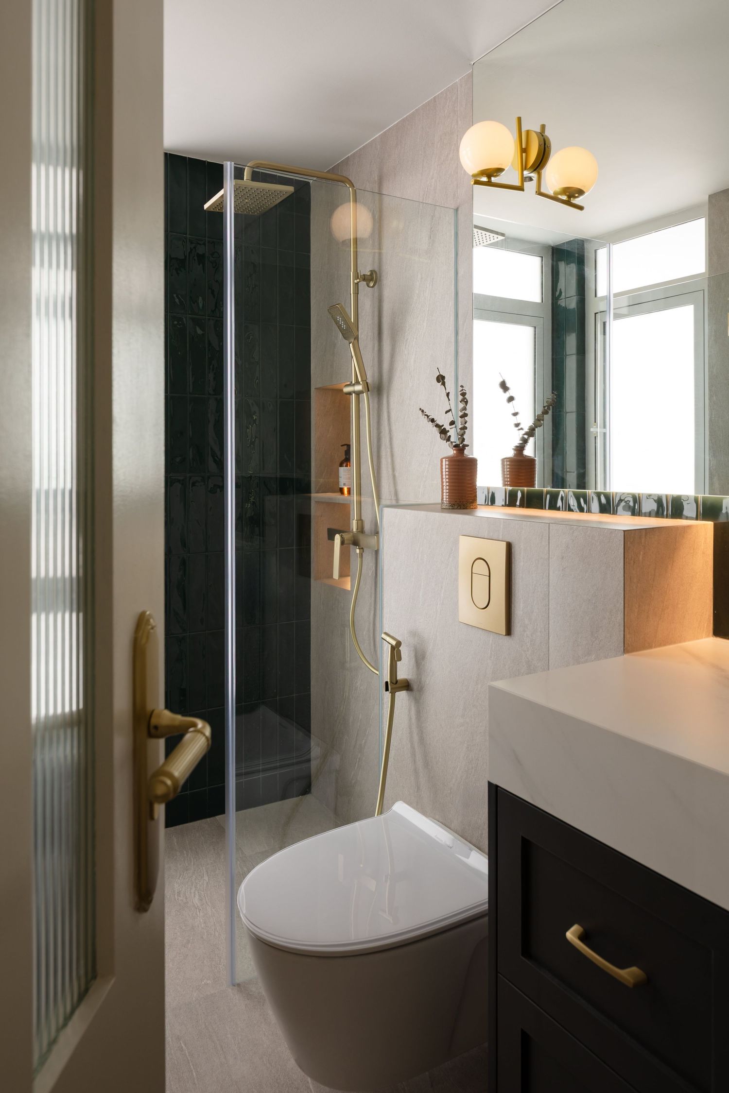 Modern luxury bathroom with dark glass shower, wall-mounted toilet, and brass fixtures against white marble walls and floors.