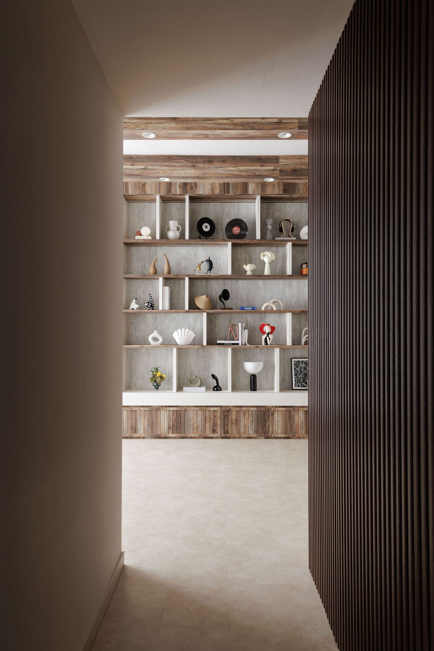 Modern wood shelving unit displaying decorative objects against a concrete wall with dramatic lighting and slat details.