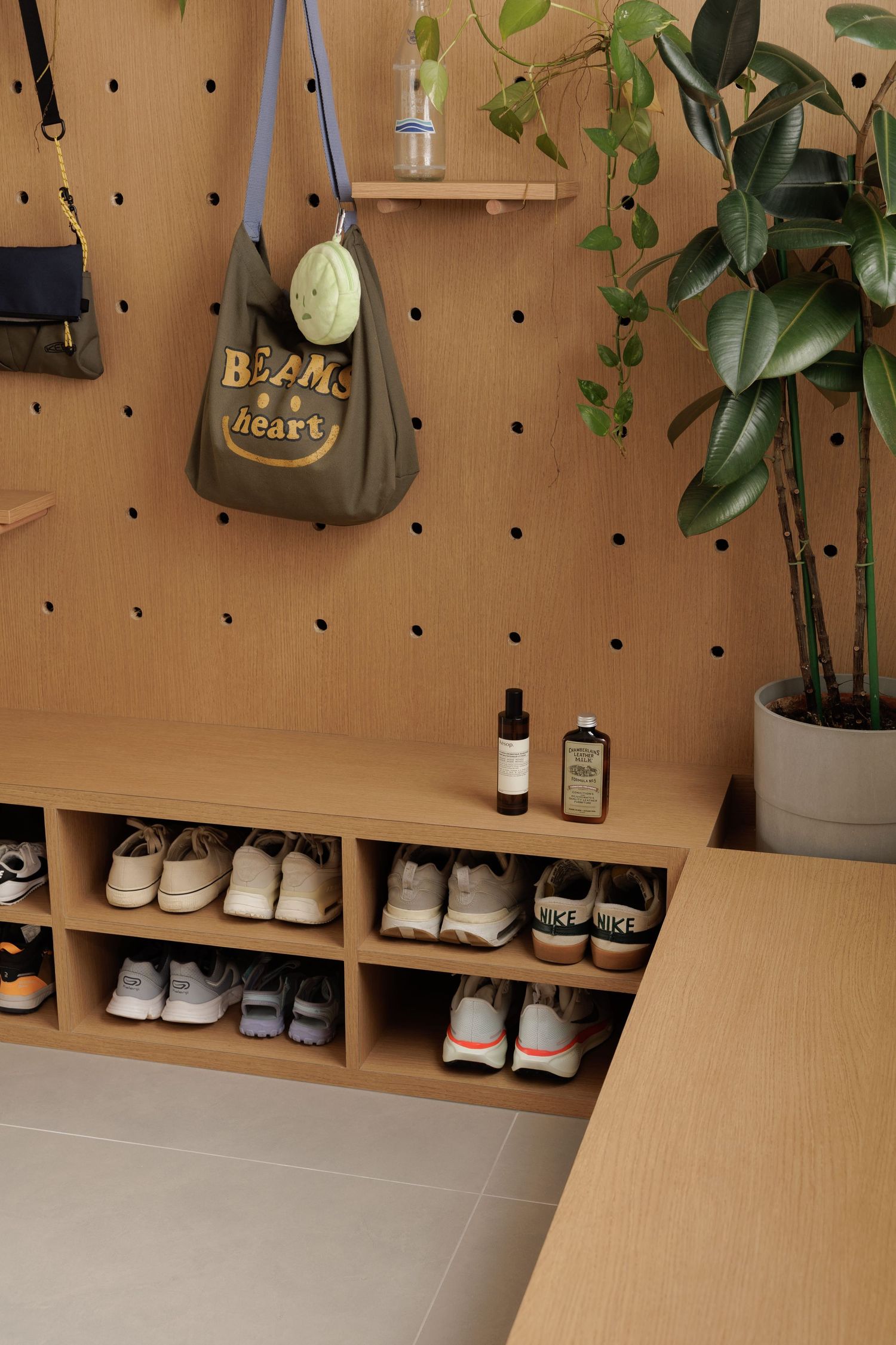 Pegboard wall display with plants, sneakers, and bottles arranged neatly on wooden shelving units.
