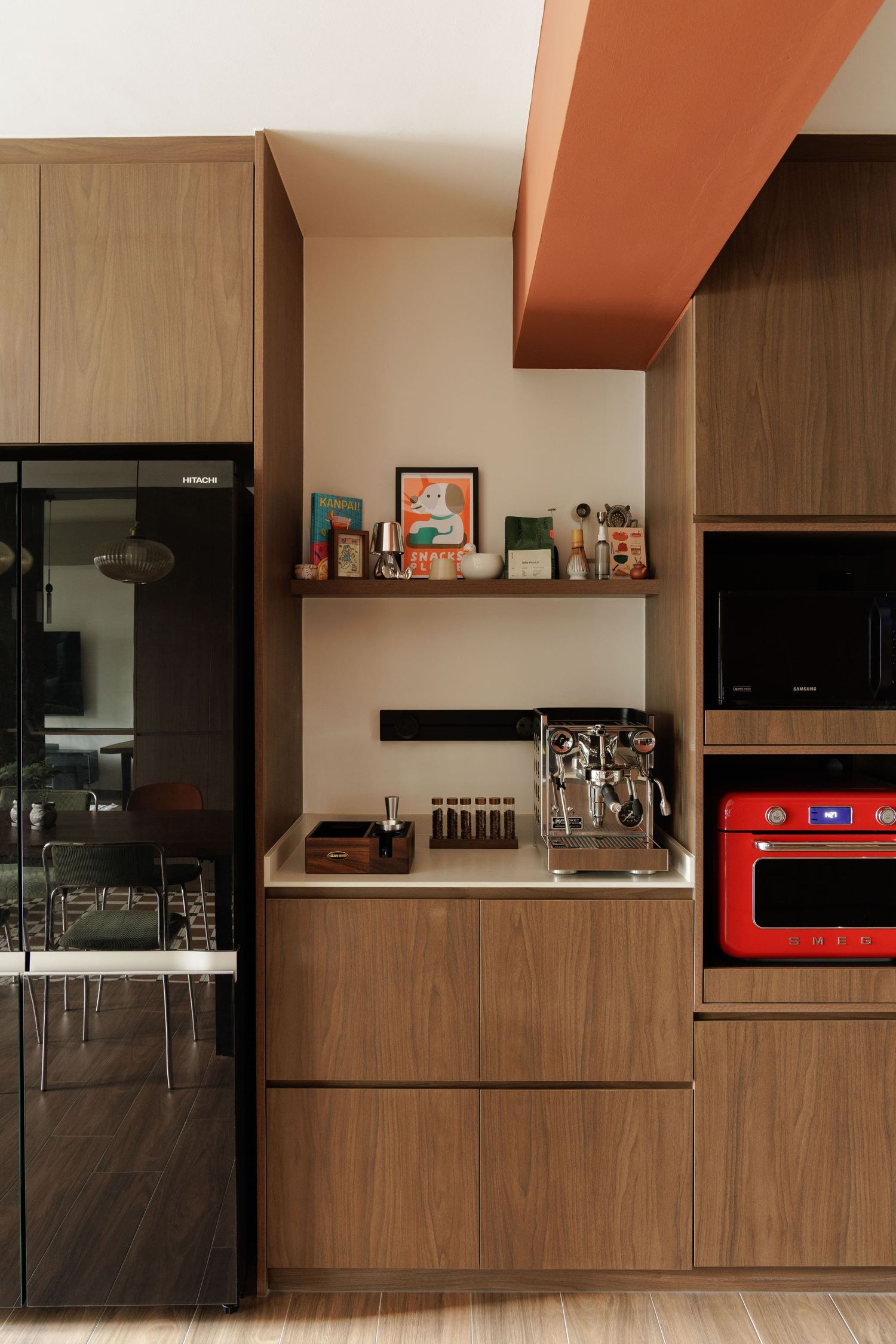 Modern kitchen interior with wooden cabinets, black appliances and orange accent beams on the ceiling.