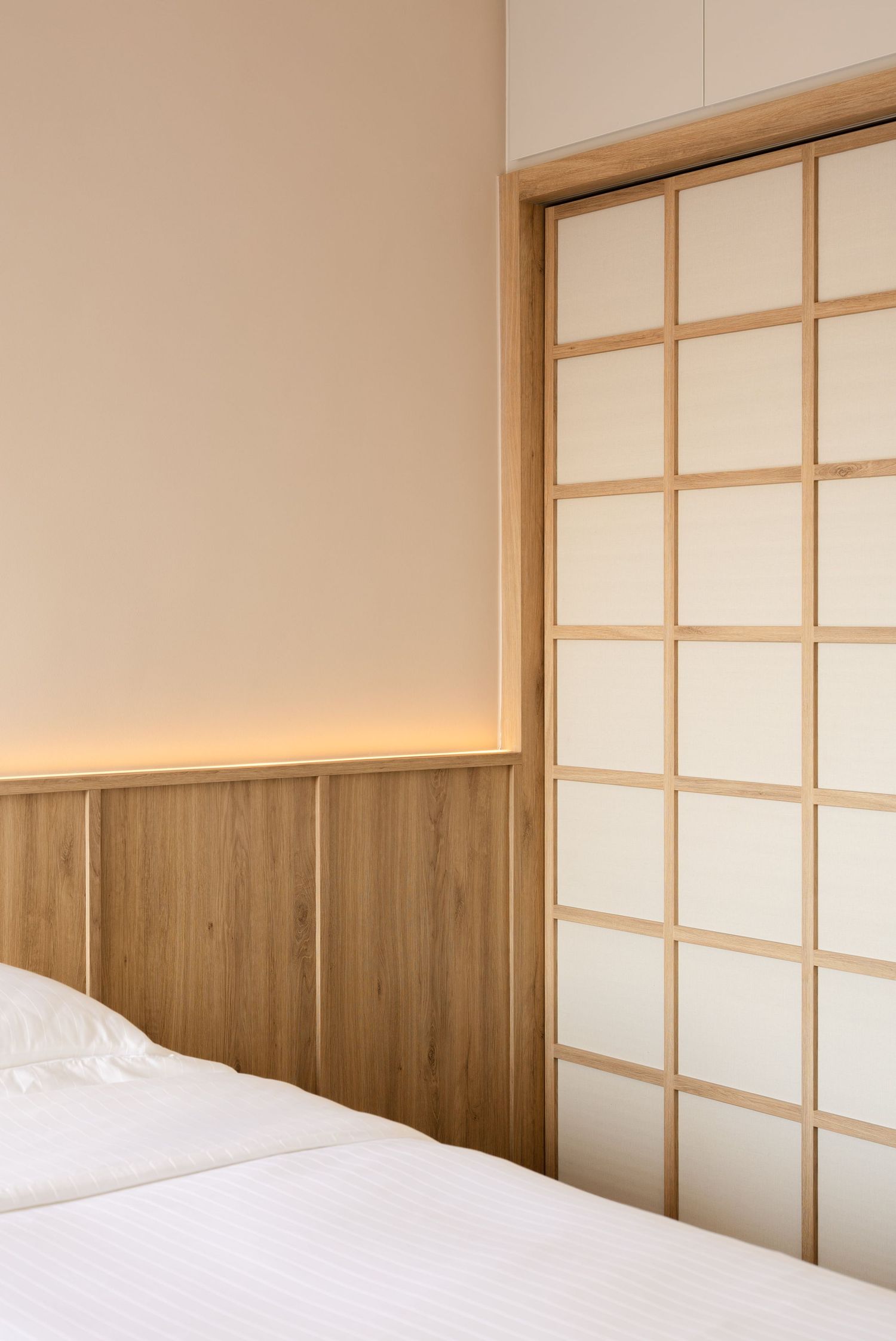 Modern Japanese-style bedroom interior with sliding shoji doors and minimalist wooden wall panels in warm lighting.