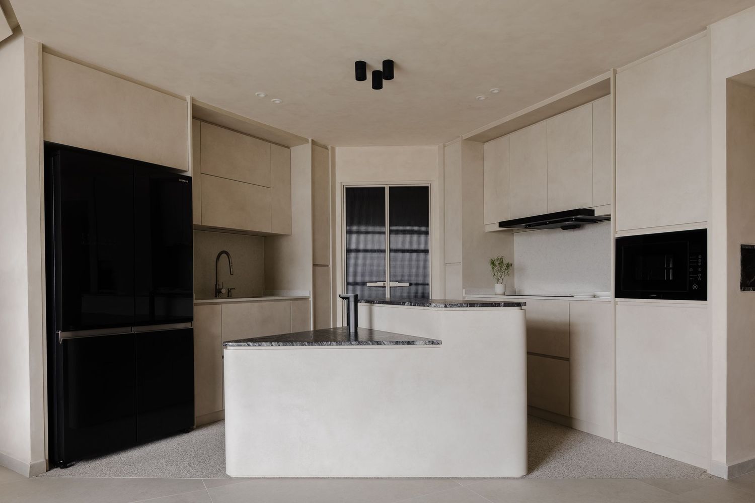 Modern minimalist kitchen with white island, light wood cabinets, and matte black appliances in a clean contemporary space.