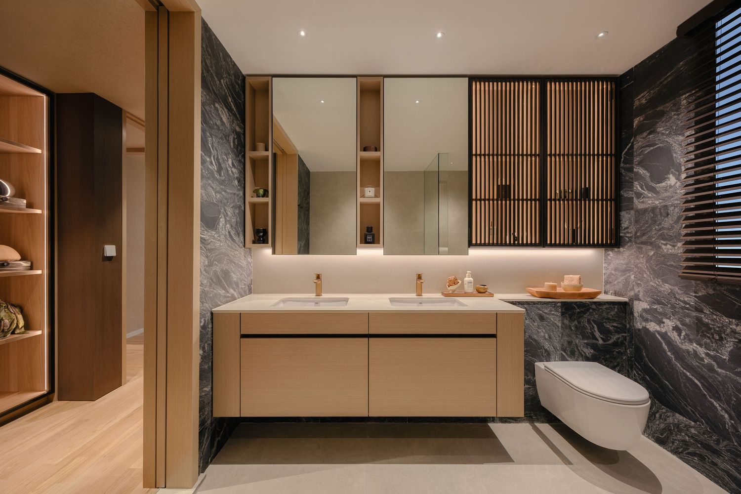 Modern luxury bathroom with dark marble walls, double-sink floating light wood vanity, backlit mirrors, and a wall-mounted toilet.