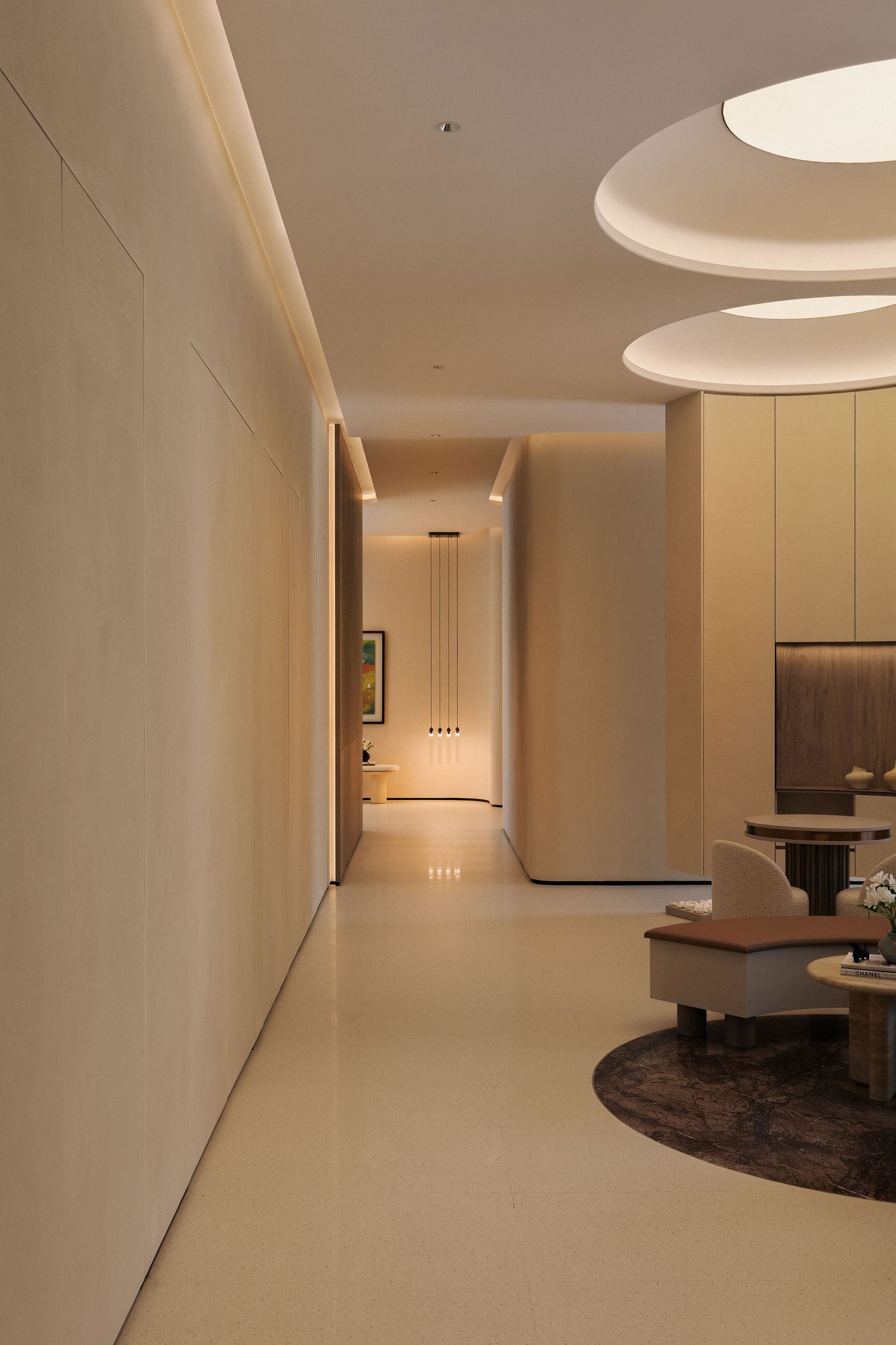 Modern luxury hotel corridor with warm lighting, circular ceiling fixtures, and elegant minimalist decor leading to a glowing hallway.