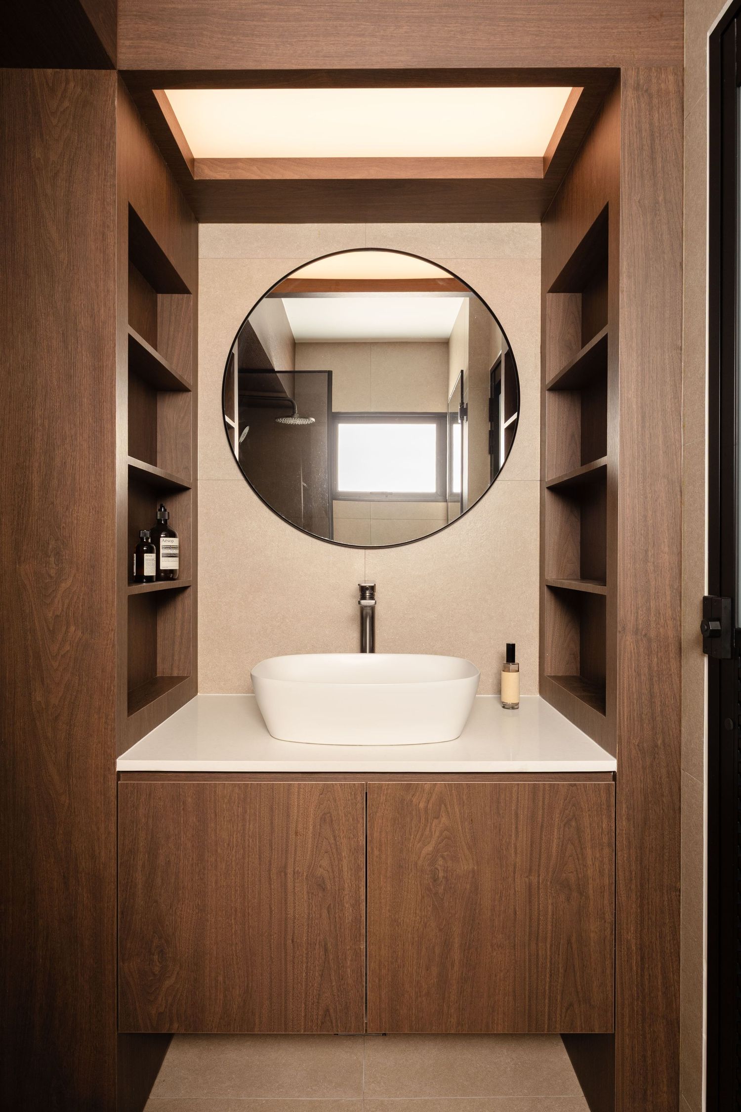 Modern bathroom interior with wooden walls and oval mirror featuring minimalist design and built-in storage shelves.