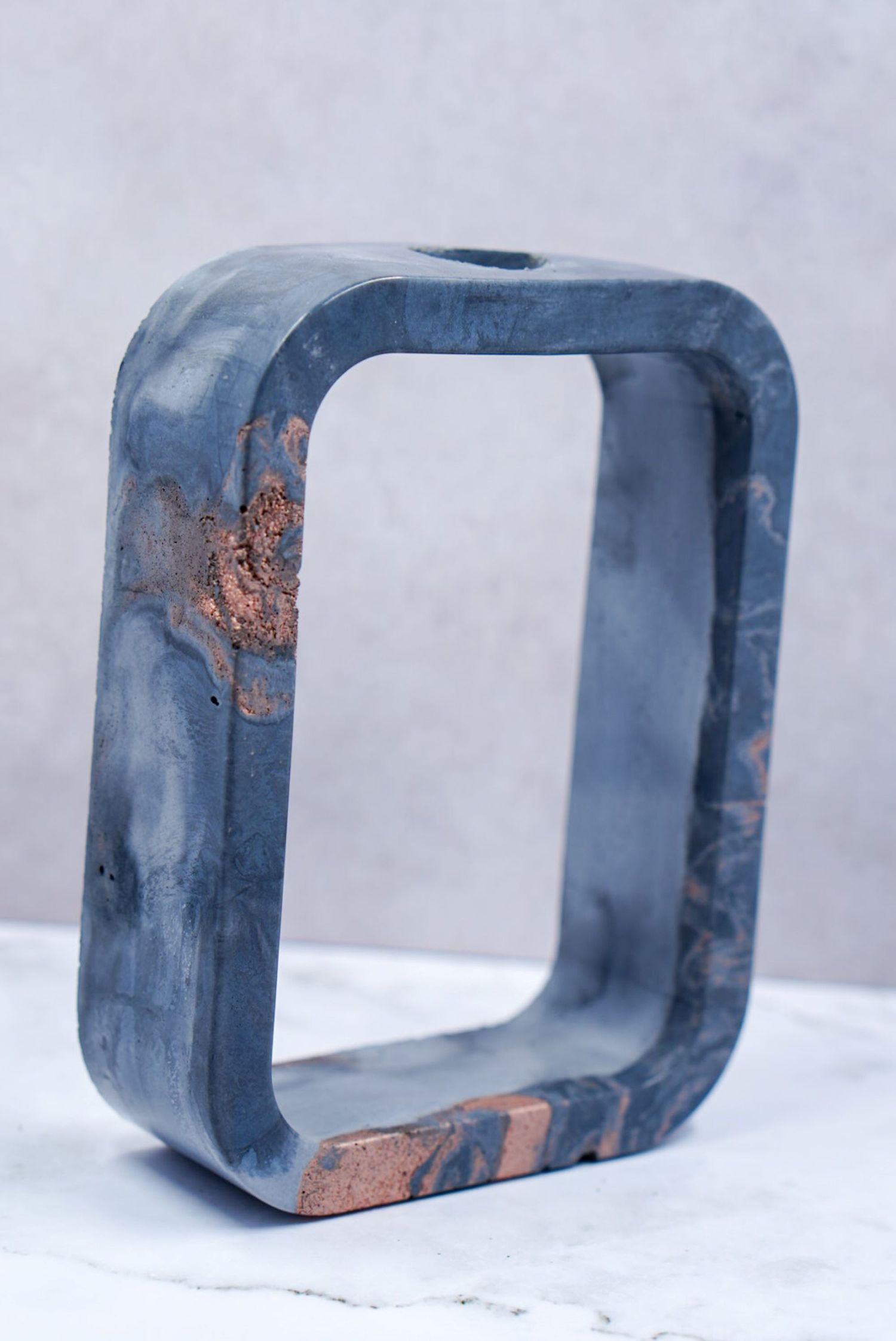 Handmade blue and copper marbled resin square frame candle holder on marble surface.