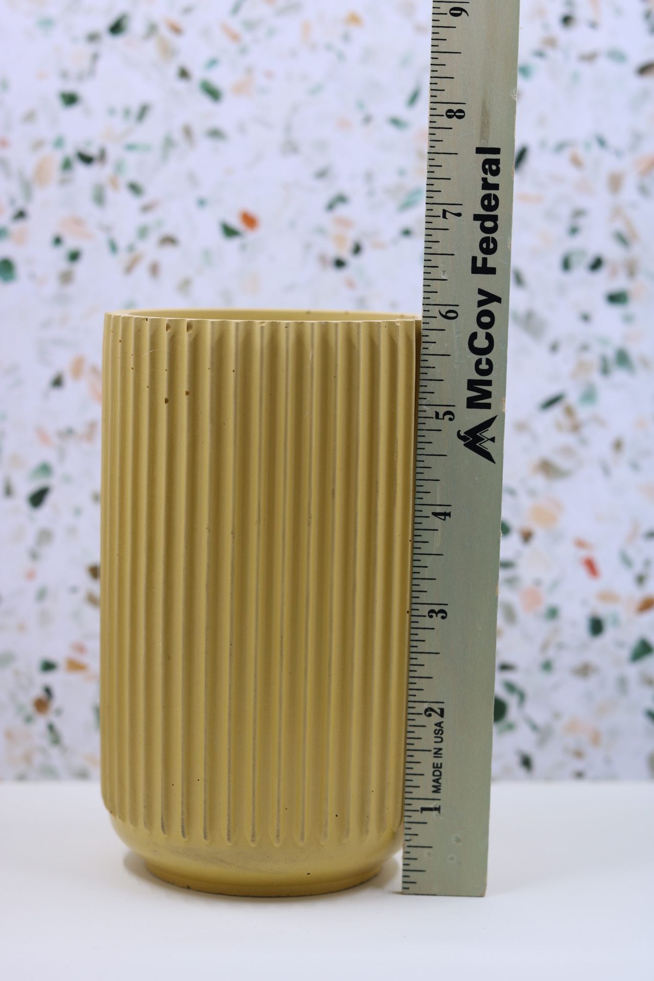 Yellow ribbed ceramic vase measuring approximately 6 inches tall next to McCoy Federal ruler.