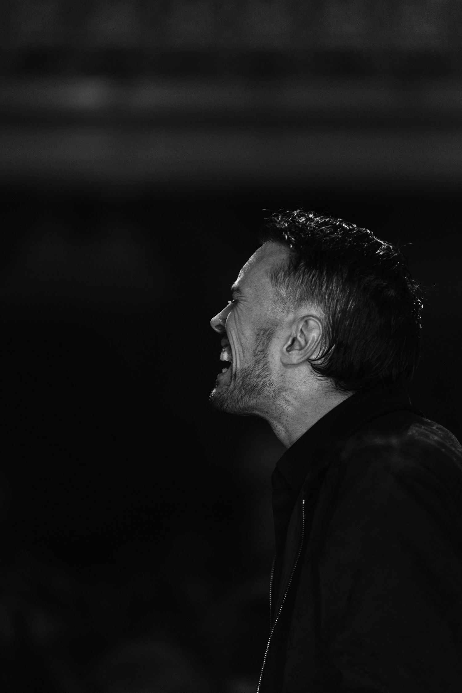 Black and white side profile of a man singing passionately at a Christian worship concert.