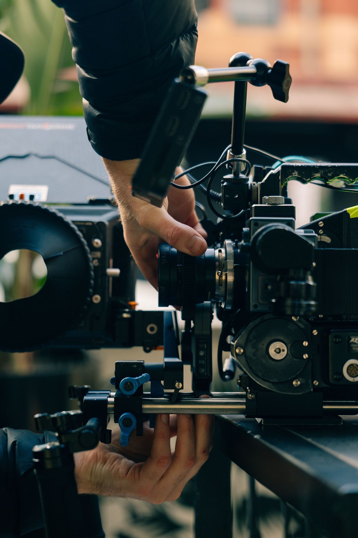 Camera operator adjusting professional cinema camera on a dolly track system outdoors.