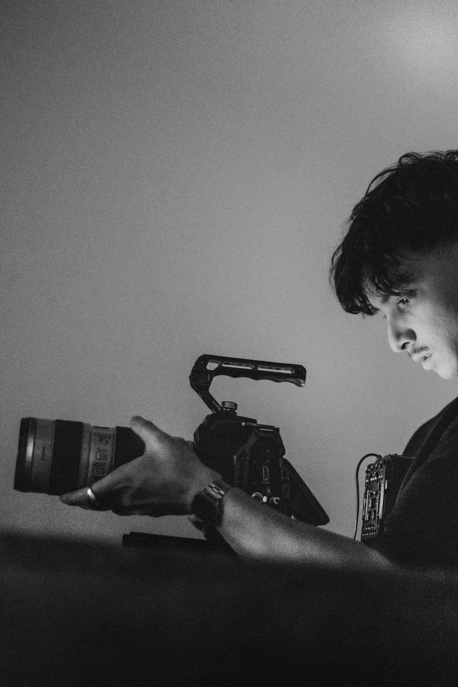 Black and white portrait of a young man holding a professional cinema camera with cage.