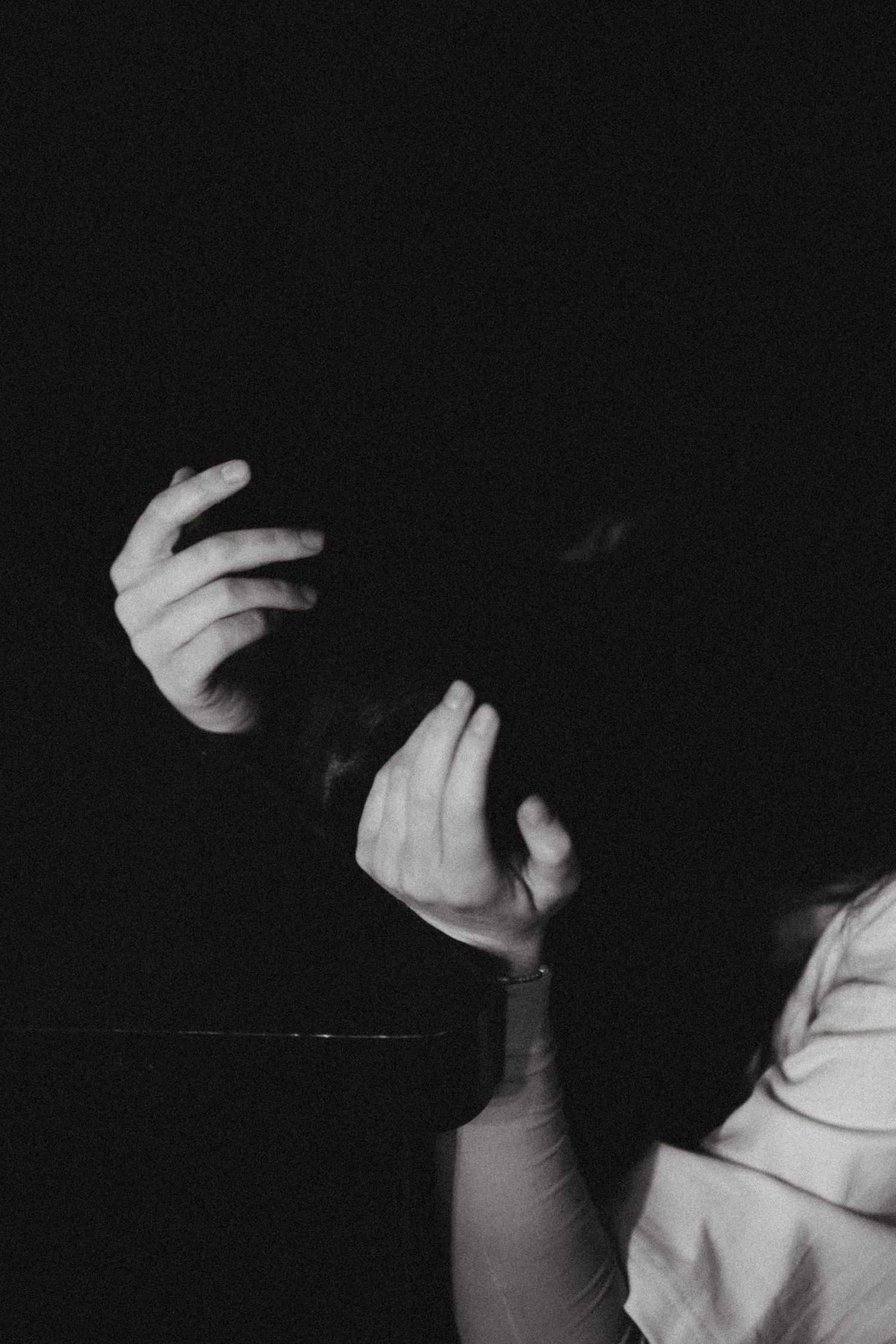Black and white photo of a person holding their head in distress, dramatic dark background.