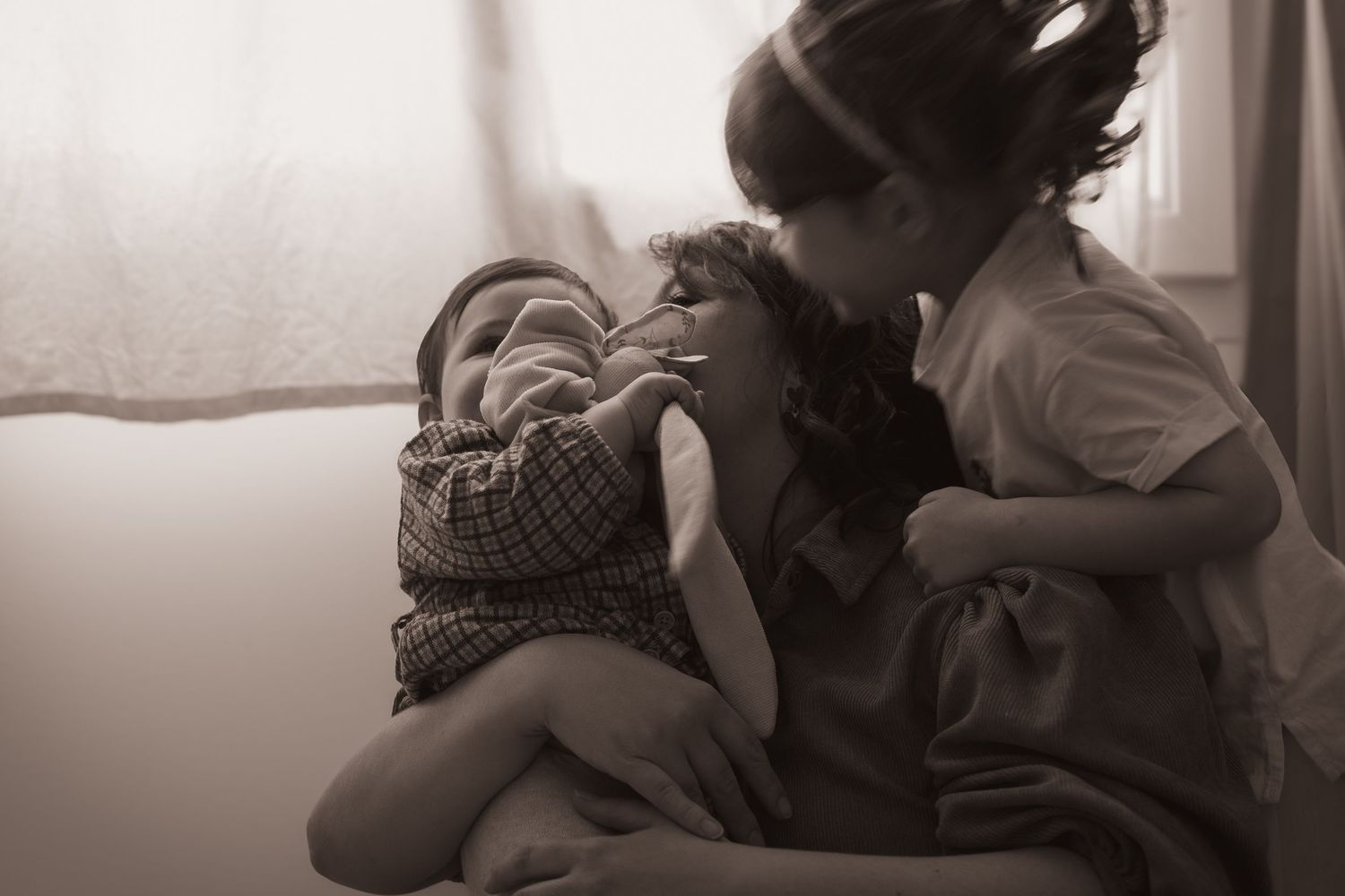 Moment de tendresse entre deux enfants à la maison, photographie lifestyle d'une fratrie en noir et blanc.