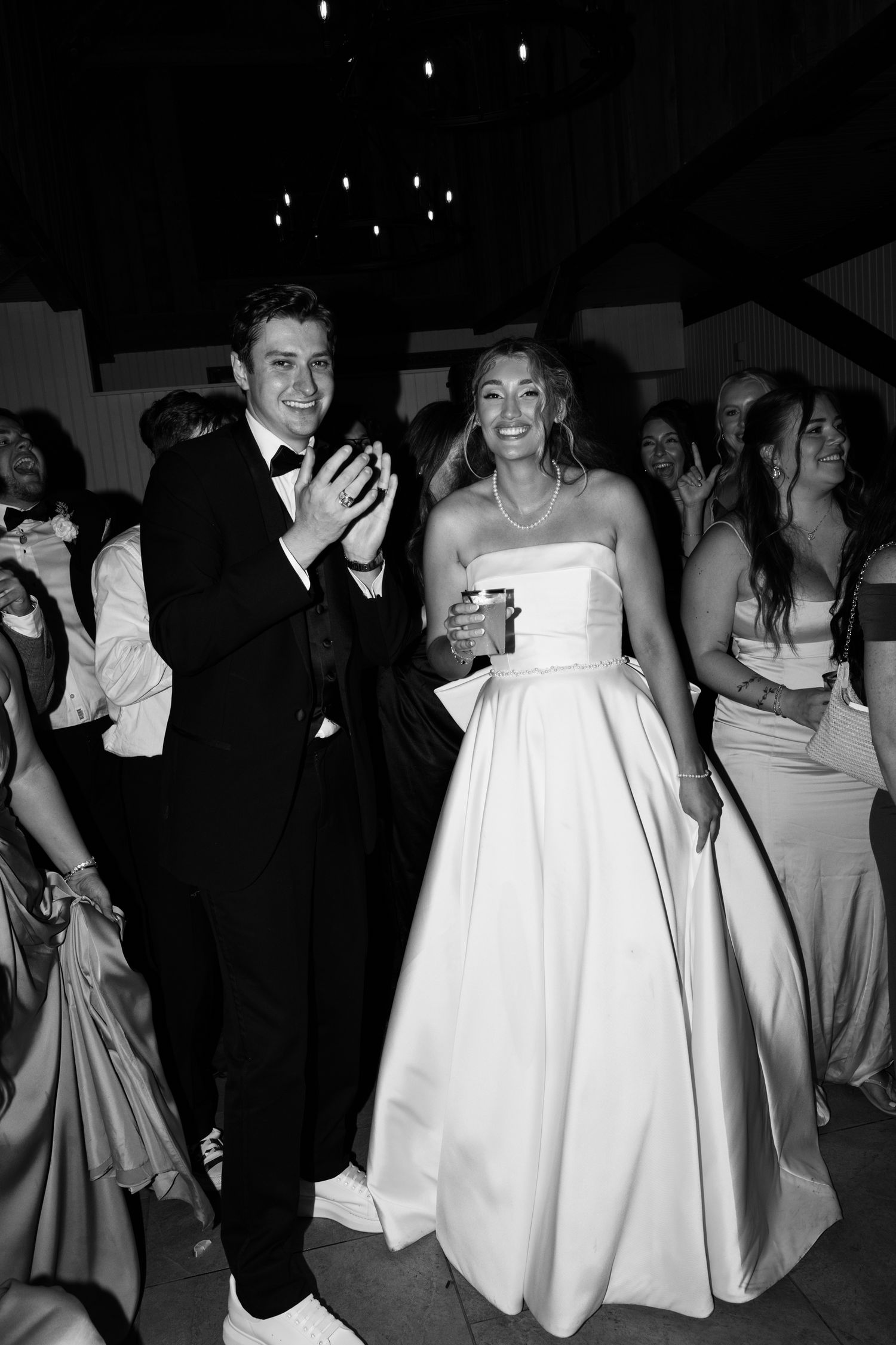 Joyful bride in strapless white ball gown and groom in tuxedo celebrate on the dance floor at their wedding reception.