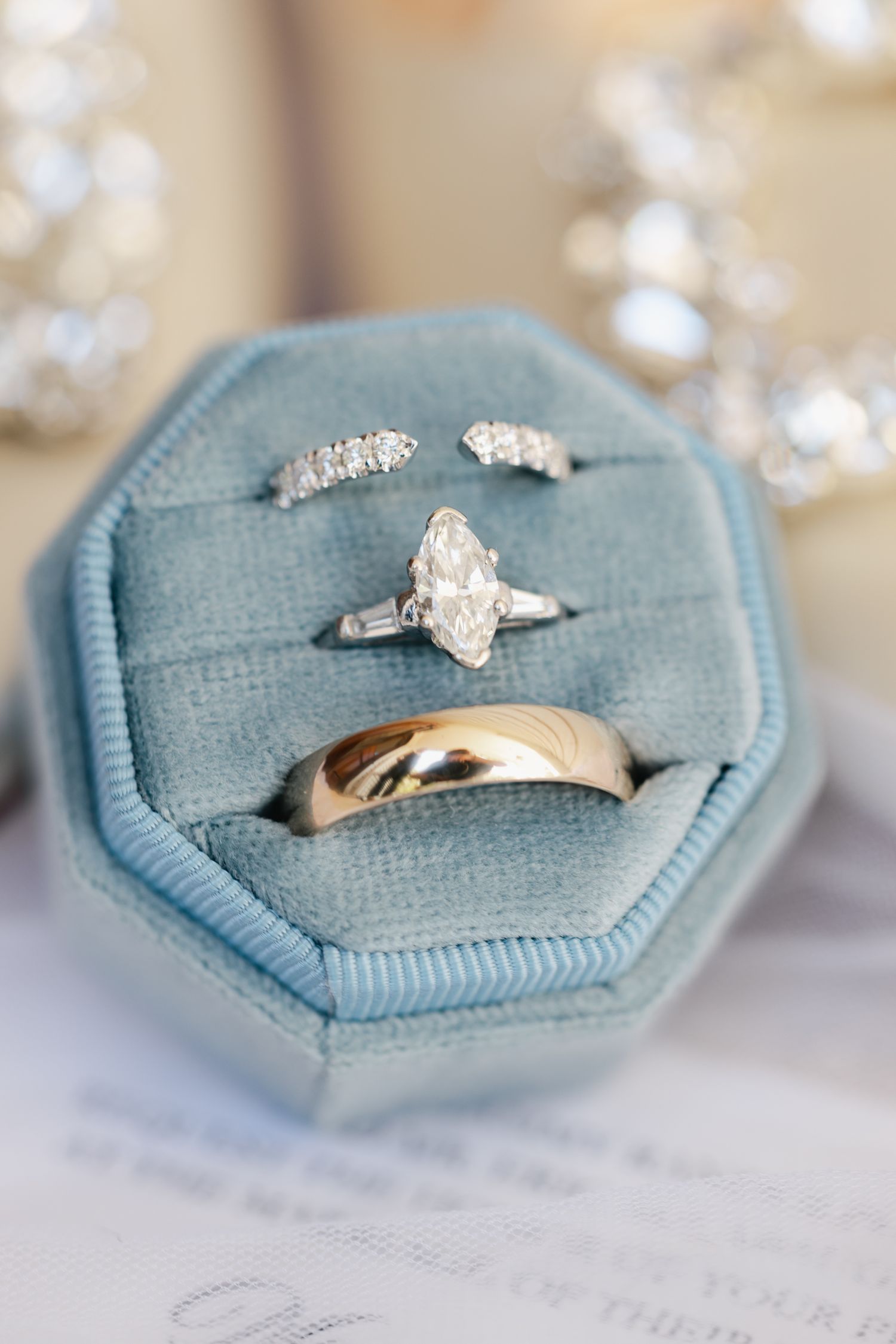 Elegant wedding rings displayed in a blue velvet octagonal ring box, featuring a marquise diamond engagement ring and gold band.