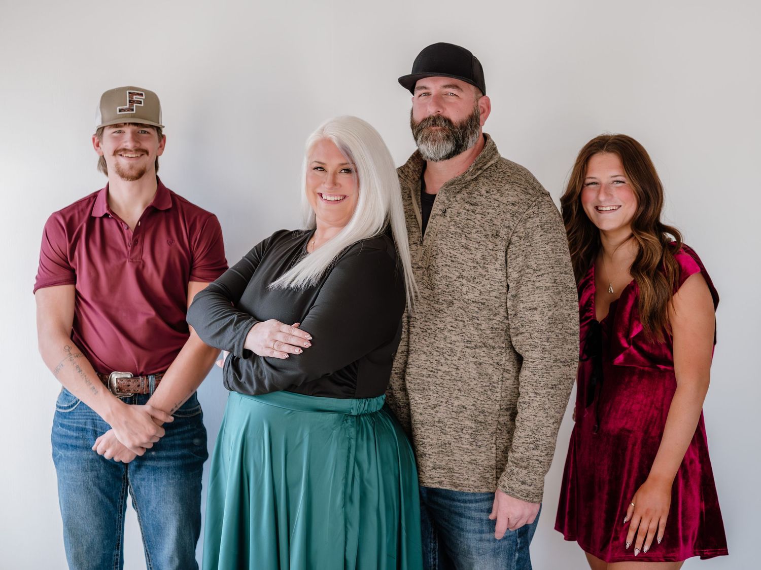 Four people posing together for a family portrait against a white background, dressed in casual elegant attire.