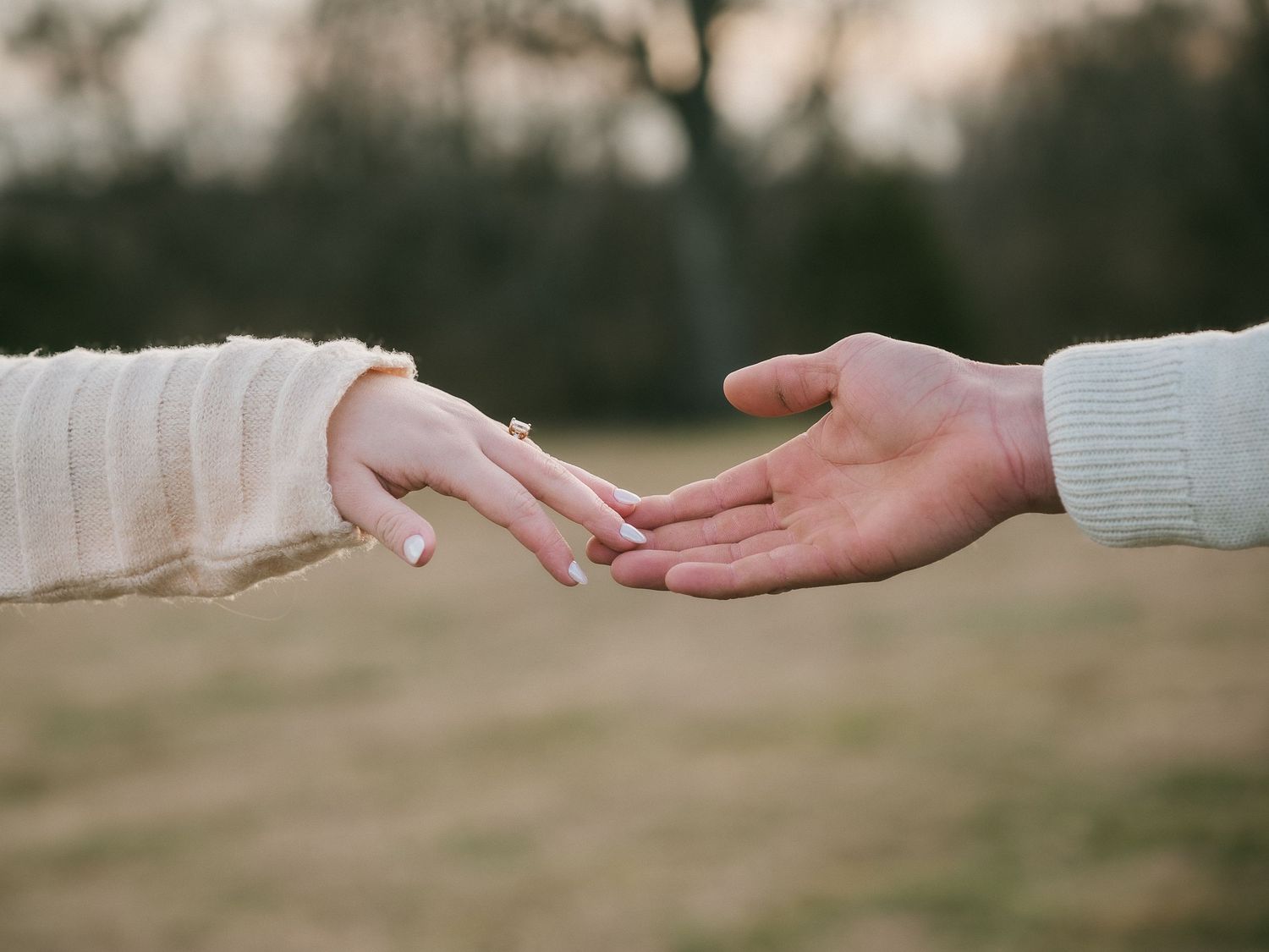 Springfield, Missouri photography engagement session, touching hands, wearing an engagement ring, with blurred natural background.