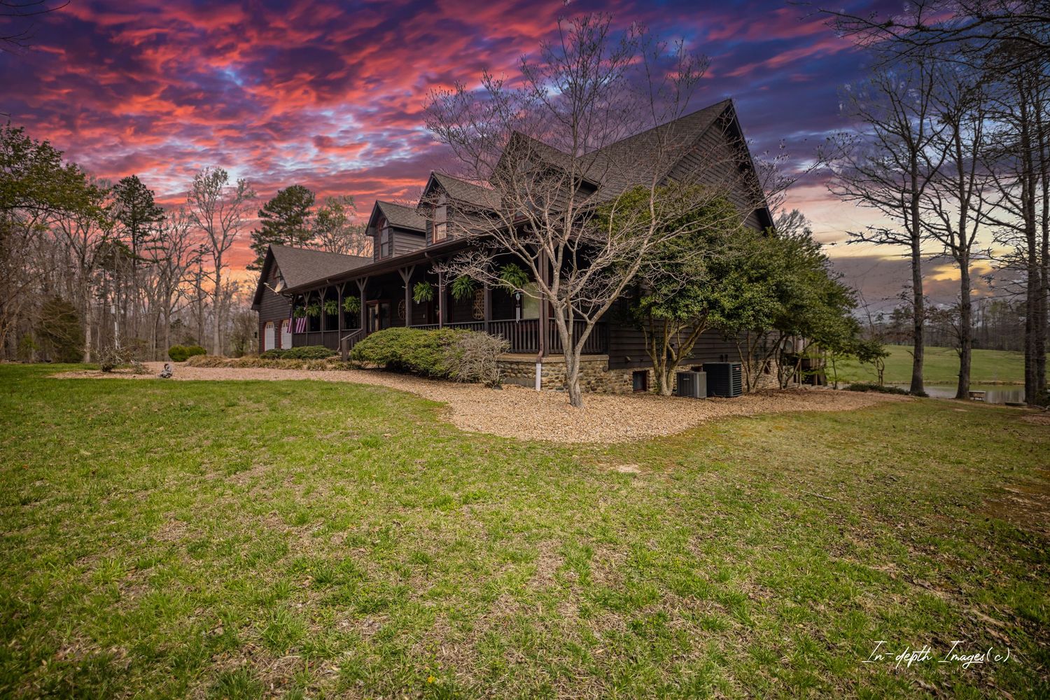 A large dark wooden lodge-style home at sunset with dramatic red and purple sky backdrop.