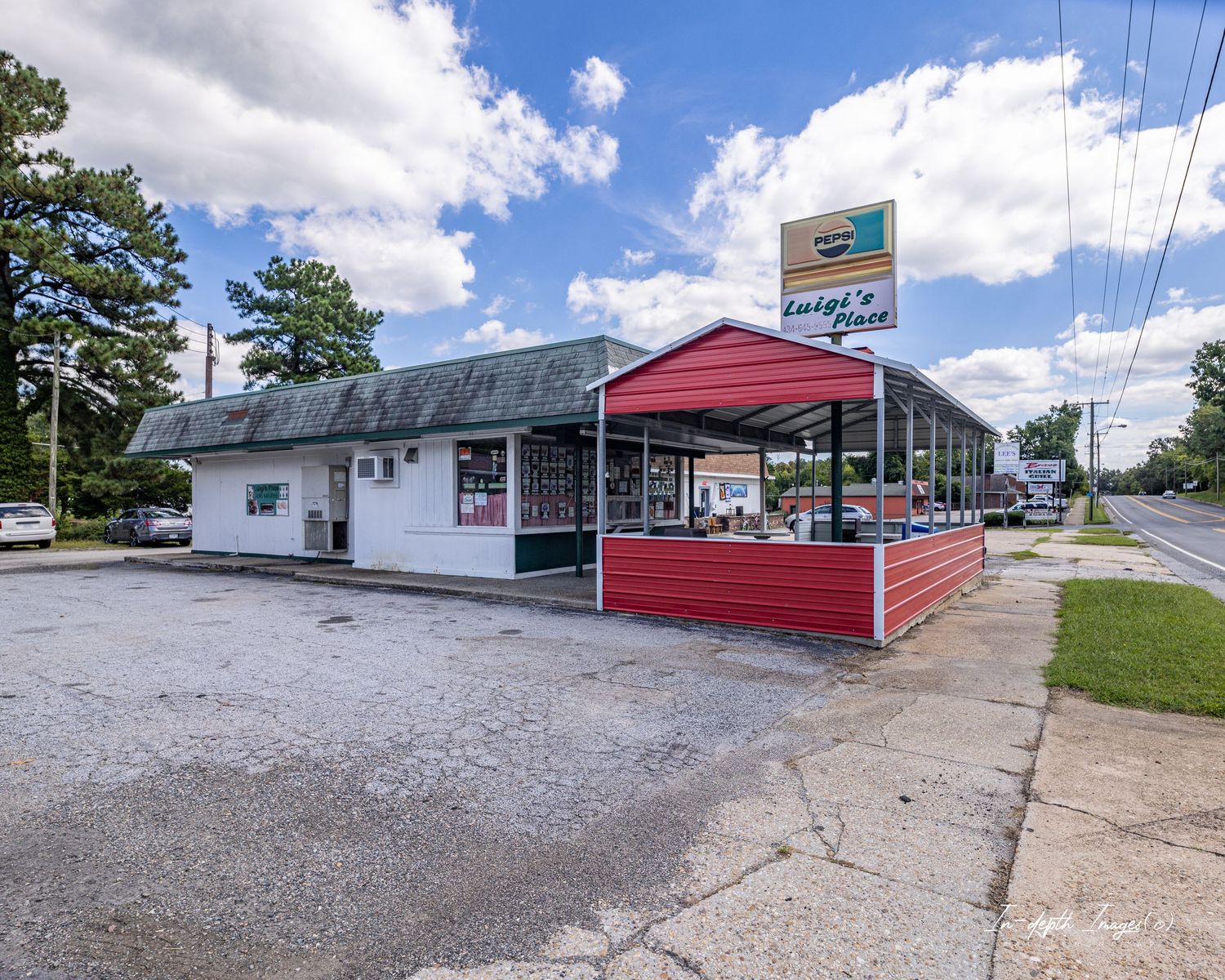 A small roadside convenience store and deli with red metal roof and outdoor signage on a sunny day.