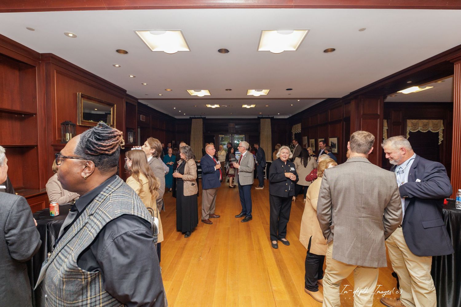 Professionals networking in an elegant wood-paneled event hall during a formal reception or corporate gathering.