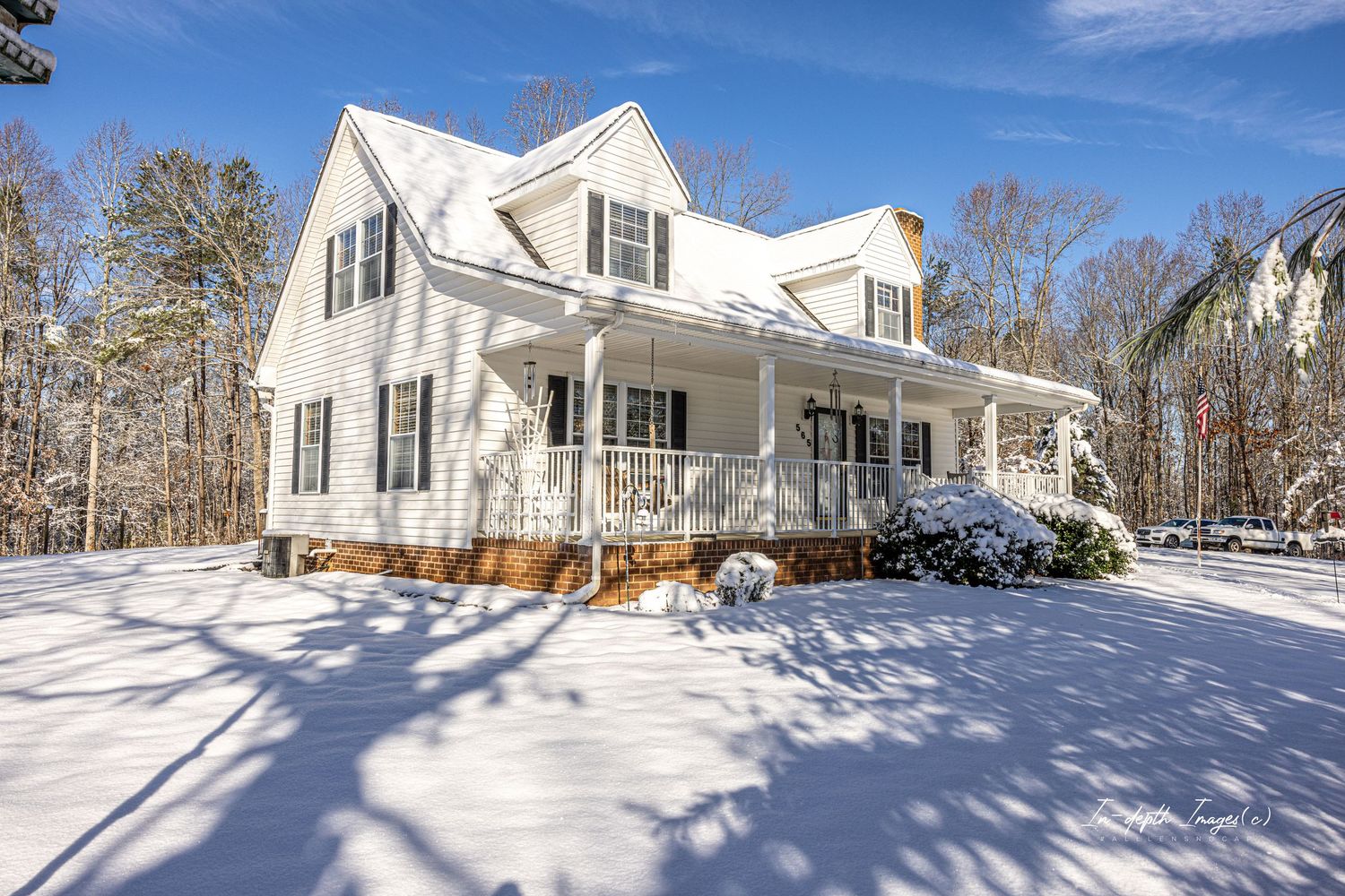 A charming white Cape Cod style home surrounded by fresh snow on a bright winter day.