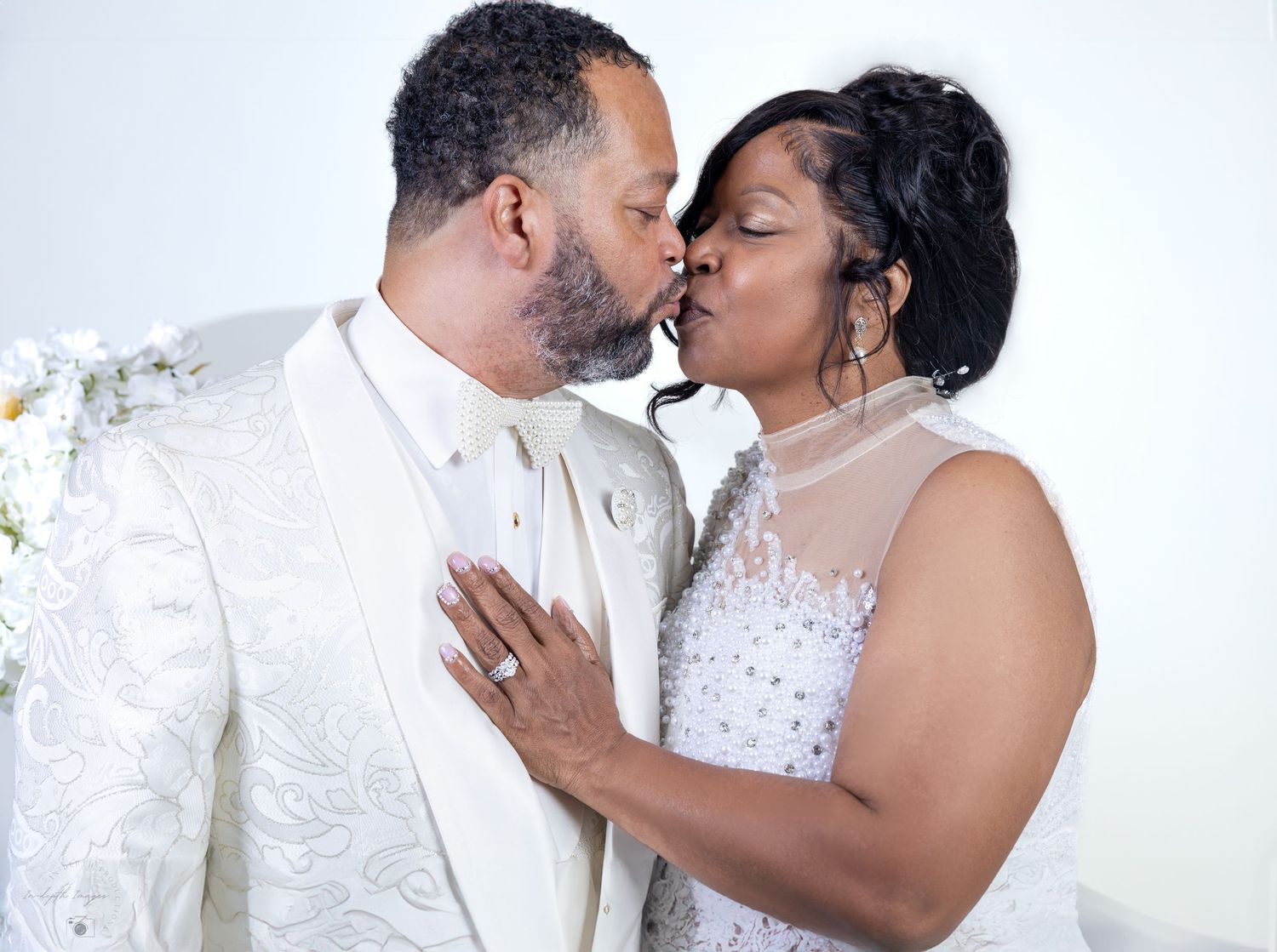 Bride and groom share a kiss at the altar during their white-themed wedding ceremony.