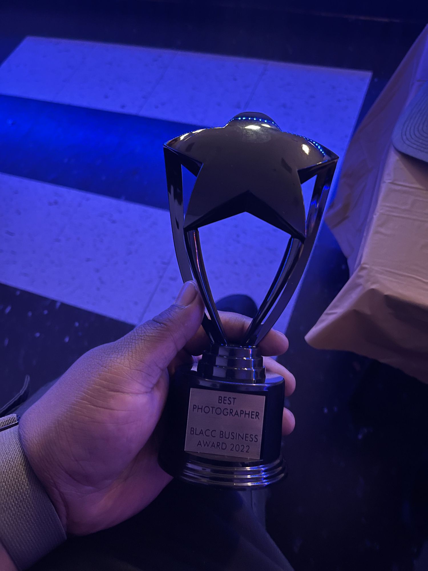 Hand holding a star-shaped Best Photographer BLACC Business Award 2022 trophy.