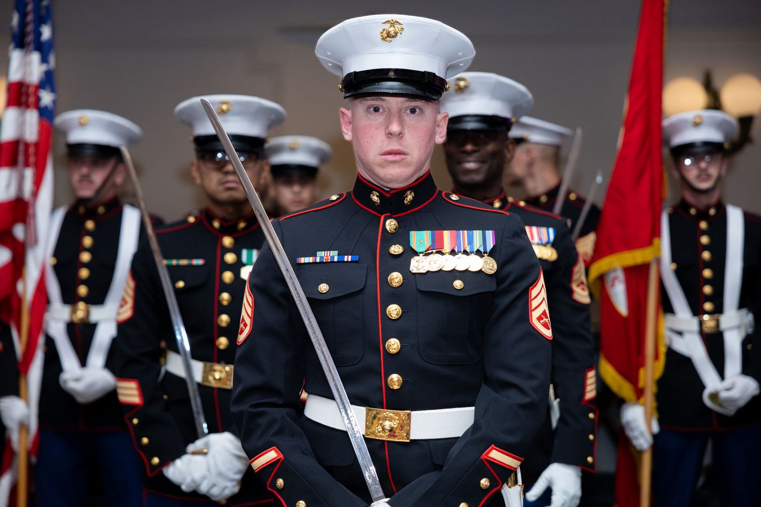 US Marine Corps color guard in dress uniforms marching in a formal military ceremony.