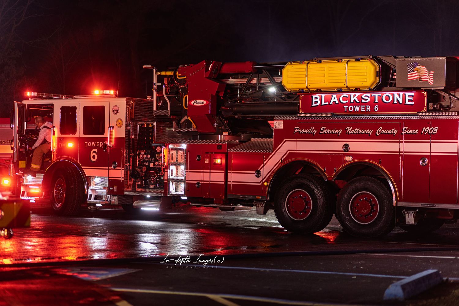 Blackstone Tower 6 fire truck responding at night with red emergency lights illuminating wet pavement.