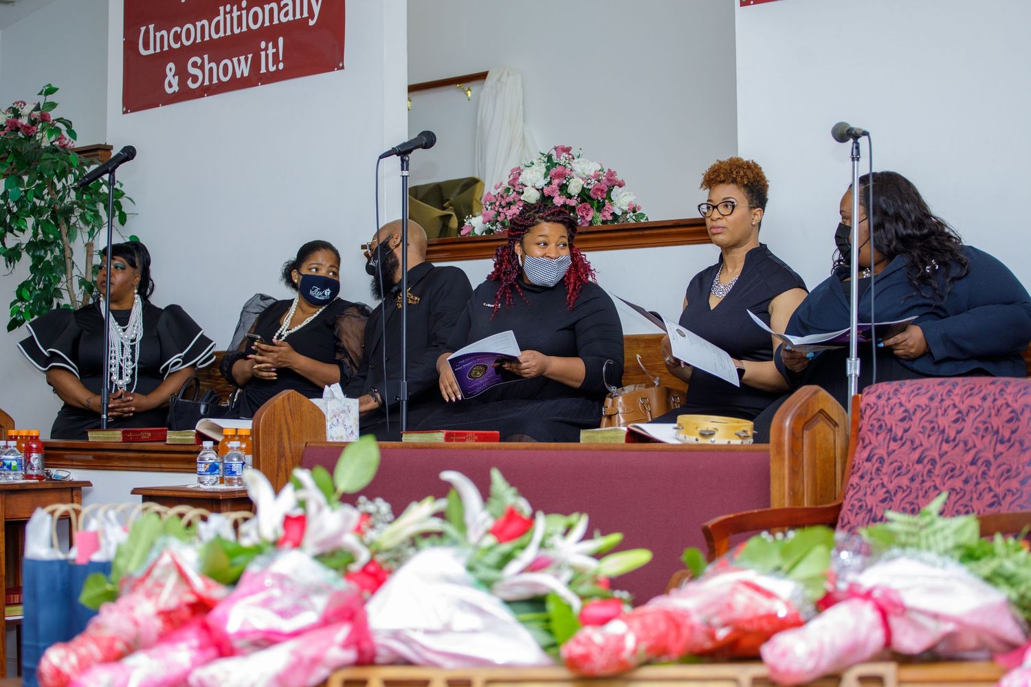 Women performing at church event with flowers in the foreground.