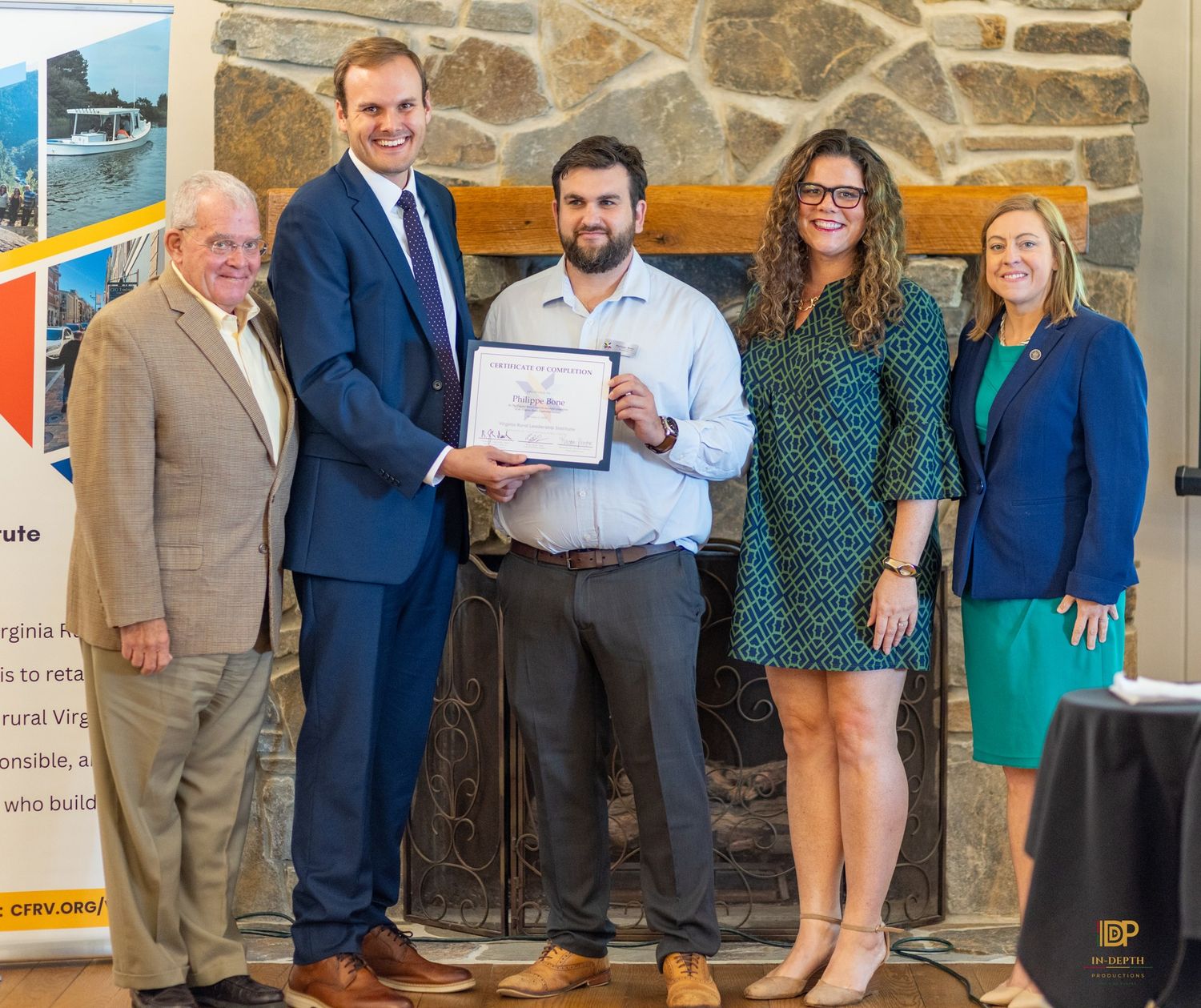A VRLI graduate holding a certificate with members of the ceremony group.