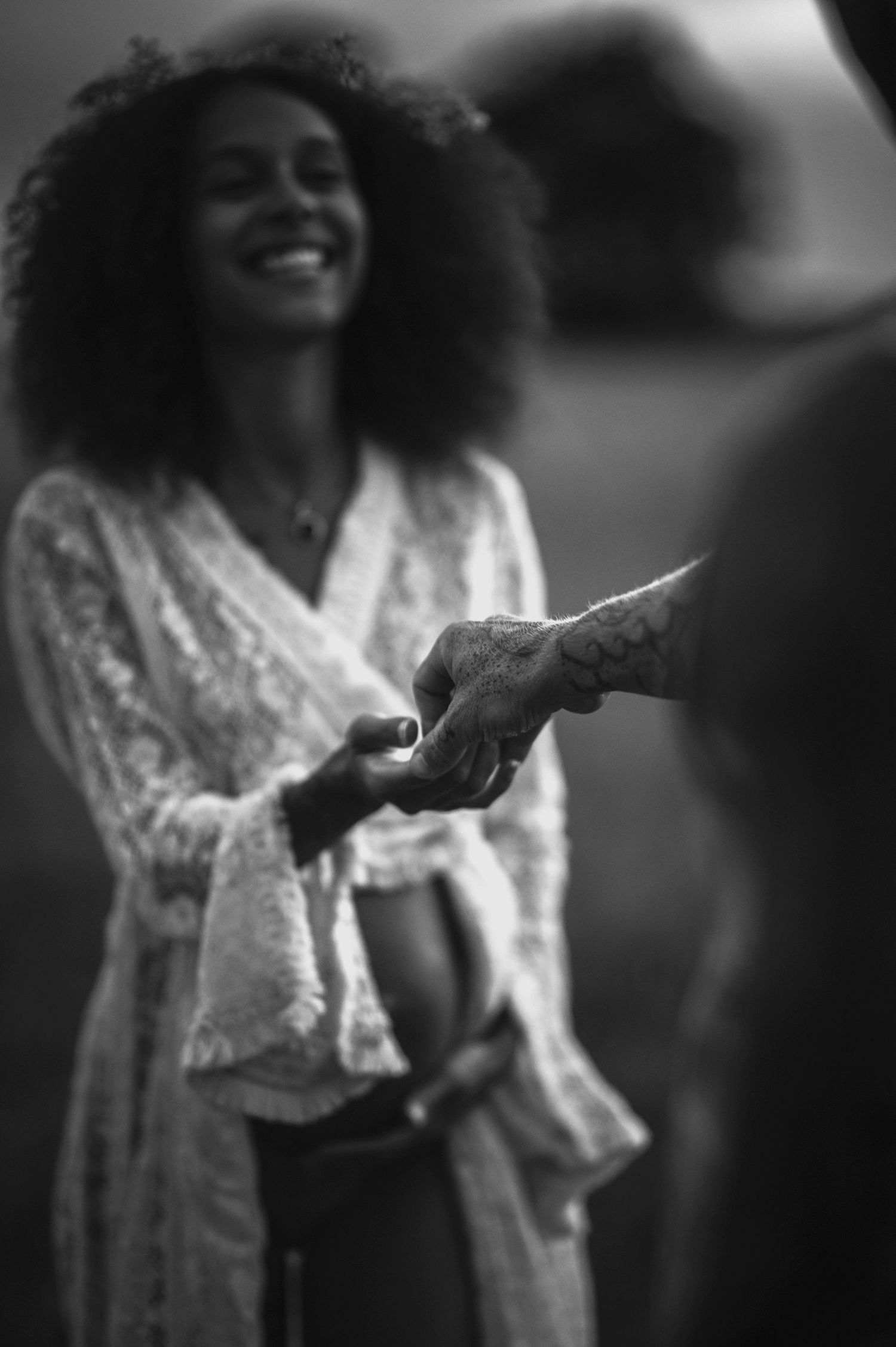 A joyful person wearing a white lace top holds hands in a candid black and white moment.