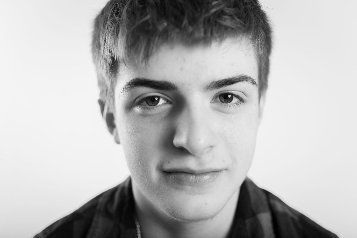 Black and white close-up portrait of a teenage boy with short hair and a subtle smile.