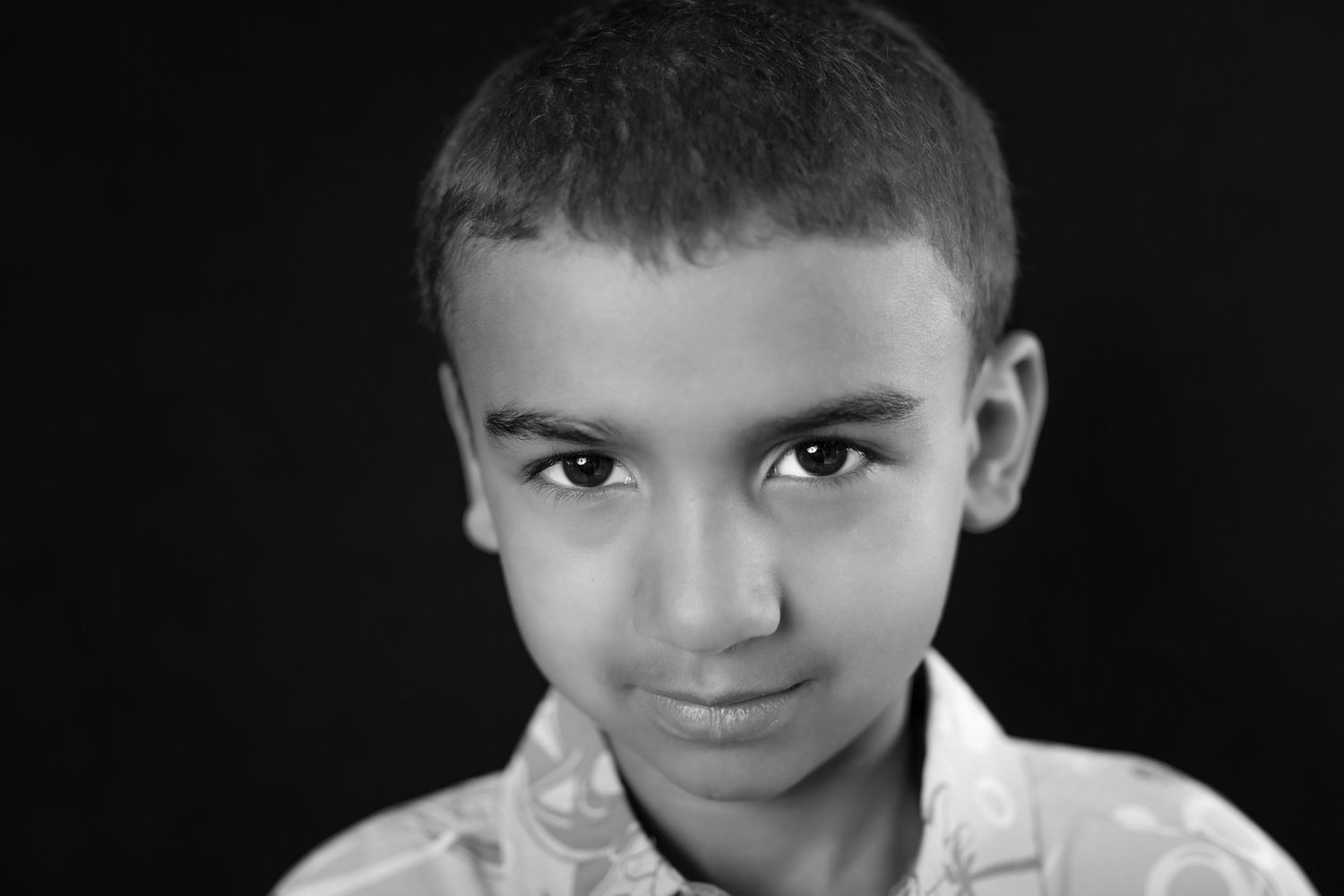 Black and white portrait of a young boy with short hair looking directly at the camera.
